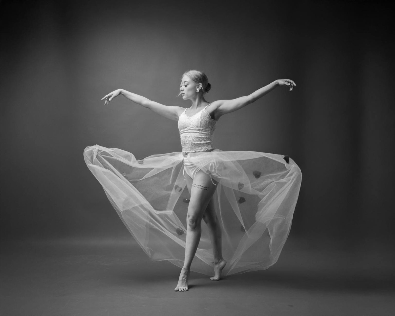 Elegant black and white portrait of a ballet dancer performing in a studio, showcasing grace and poise.