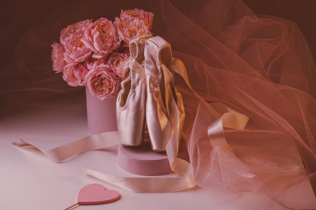 a pink vase filled with pink flowers next to a heart