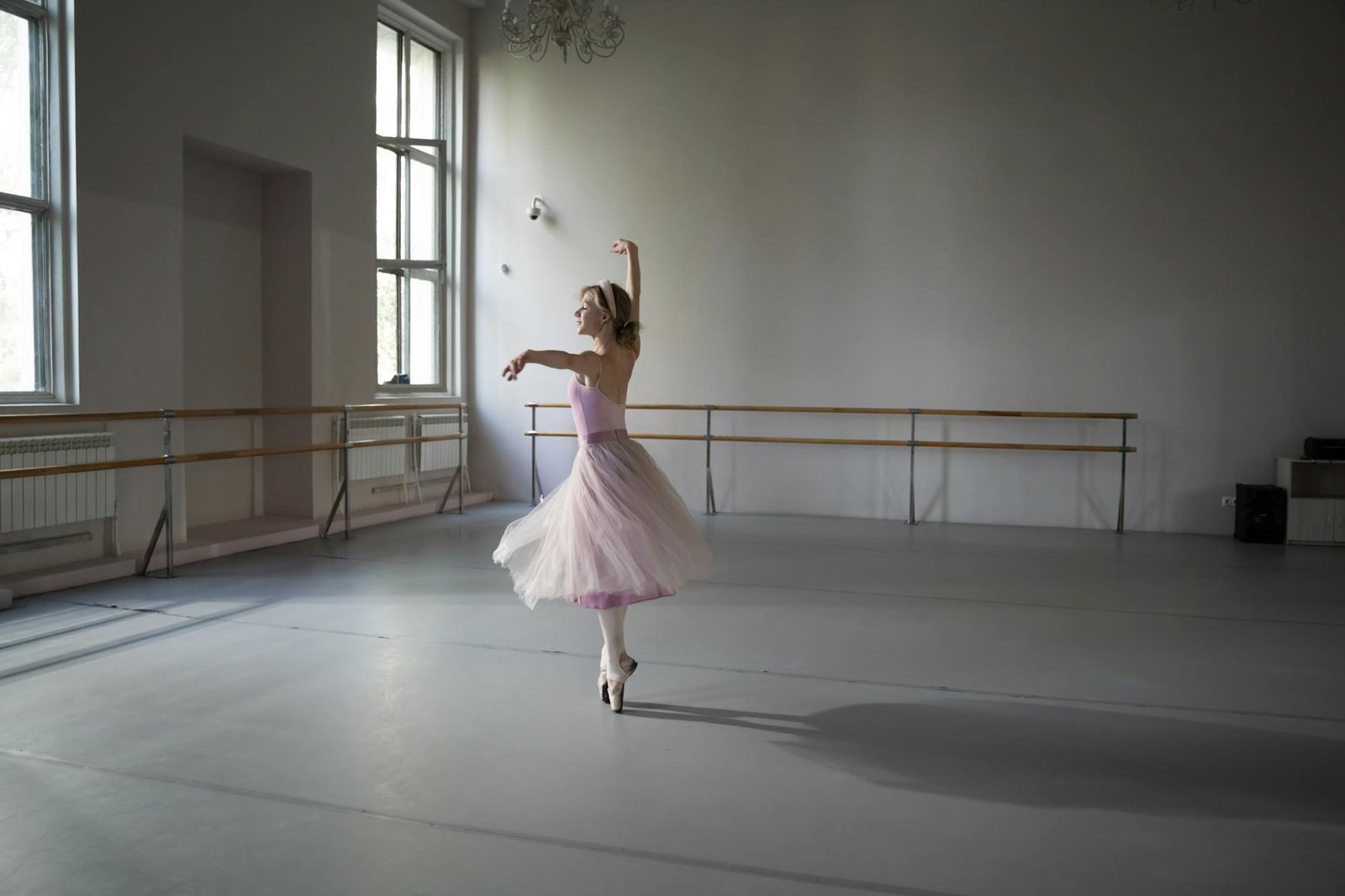 Ballerina performing in an elegant, softly lit dance studio.