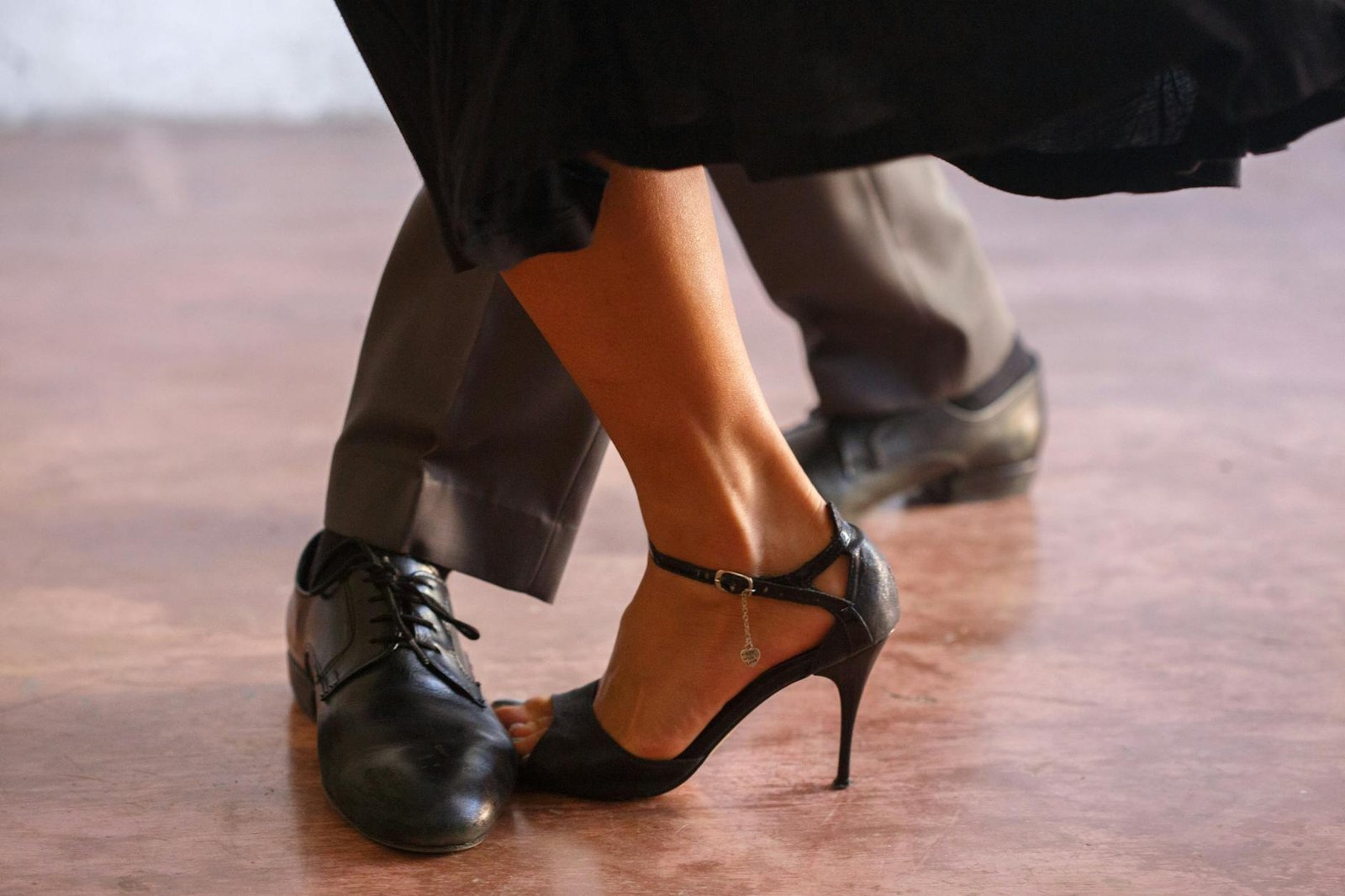 Close-up of a couple dancing tango, highlighting elegance in black shoes and high heels.