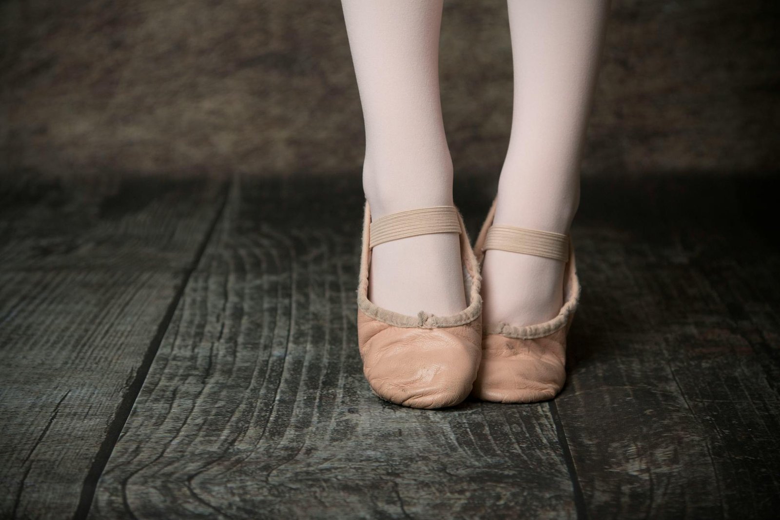 Close-up of ballet shoes worn by a dancer on a wooden floor, showcasing grace and poise.