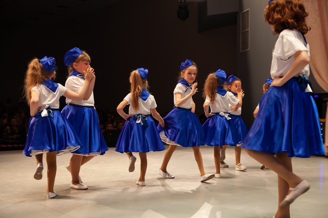 a group of girls in blue dresses dancing on a stage