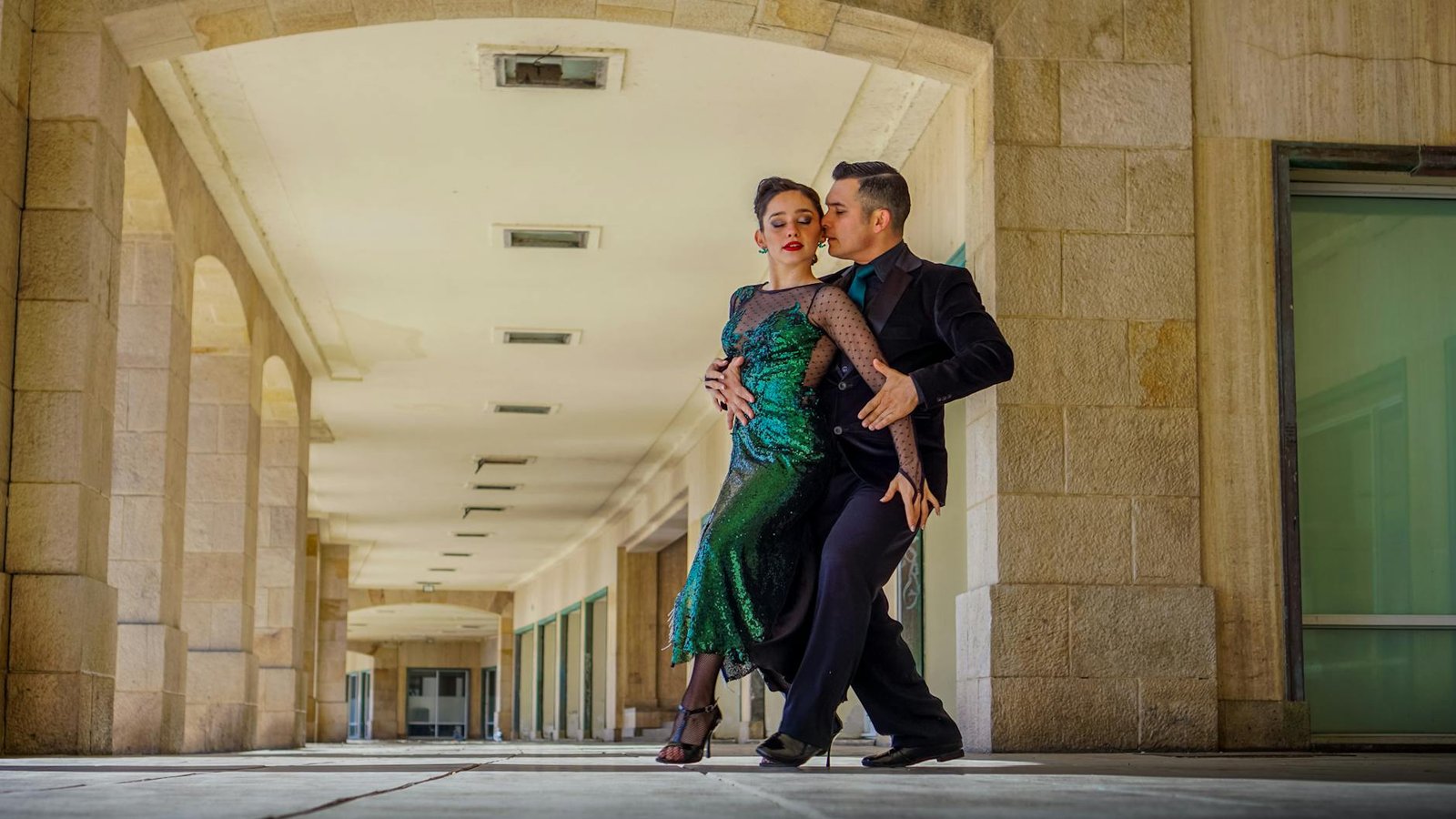 A couple performing an elegant tango dance in a stone hallway in Mar del Plata, Argentina.