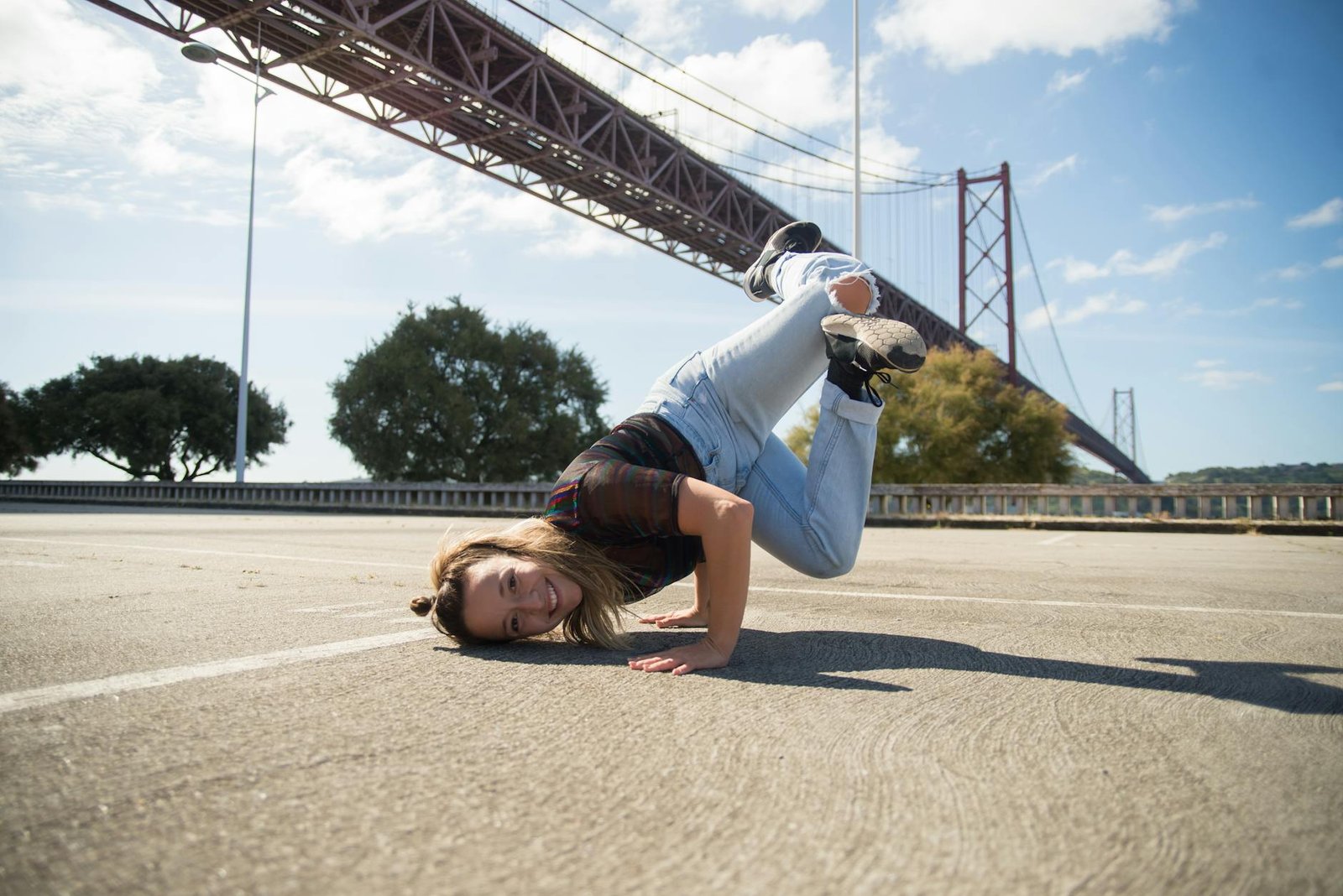 Youthful breakdancer striking a move beneath Lisbon's famous suspension bridge.