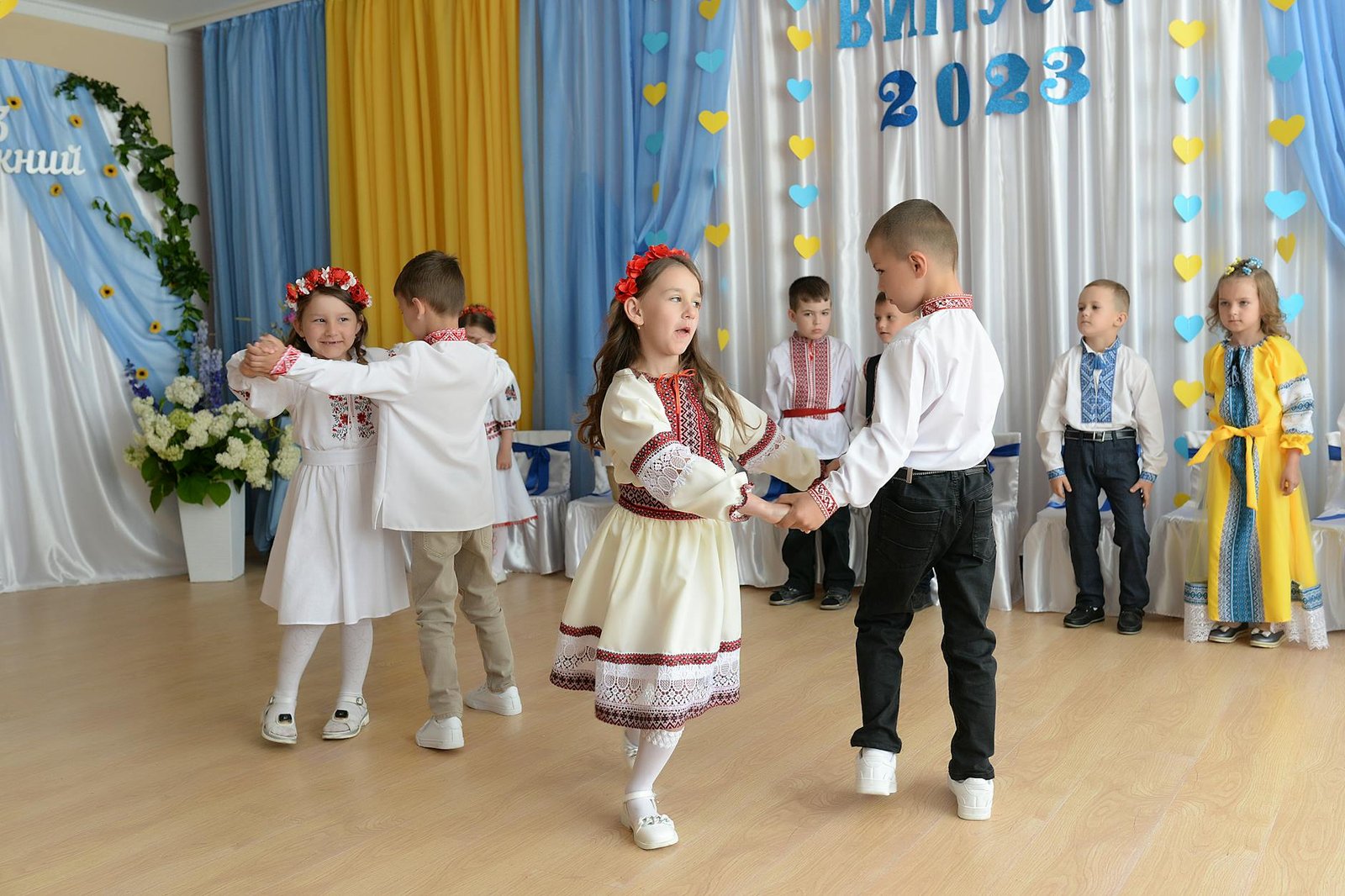 Children in traditional costumes perform a dance at a school graduation ceremony, 2023.