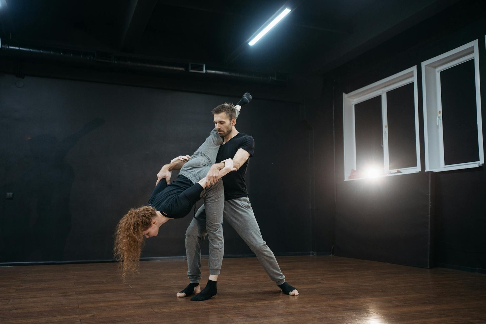 A man and woman performing an expressive dance routine in a studio with wooden floors.