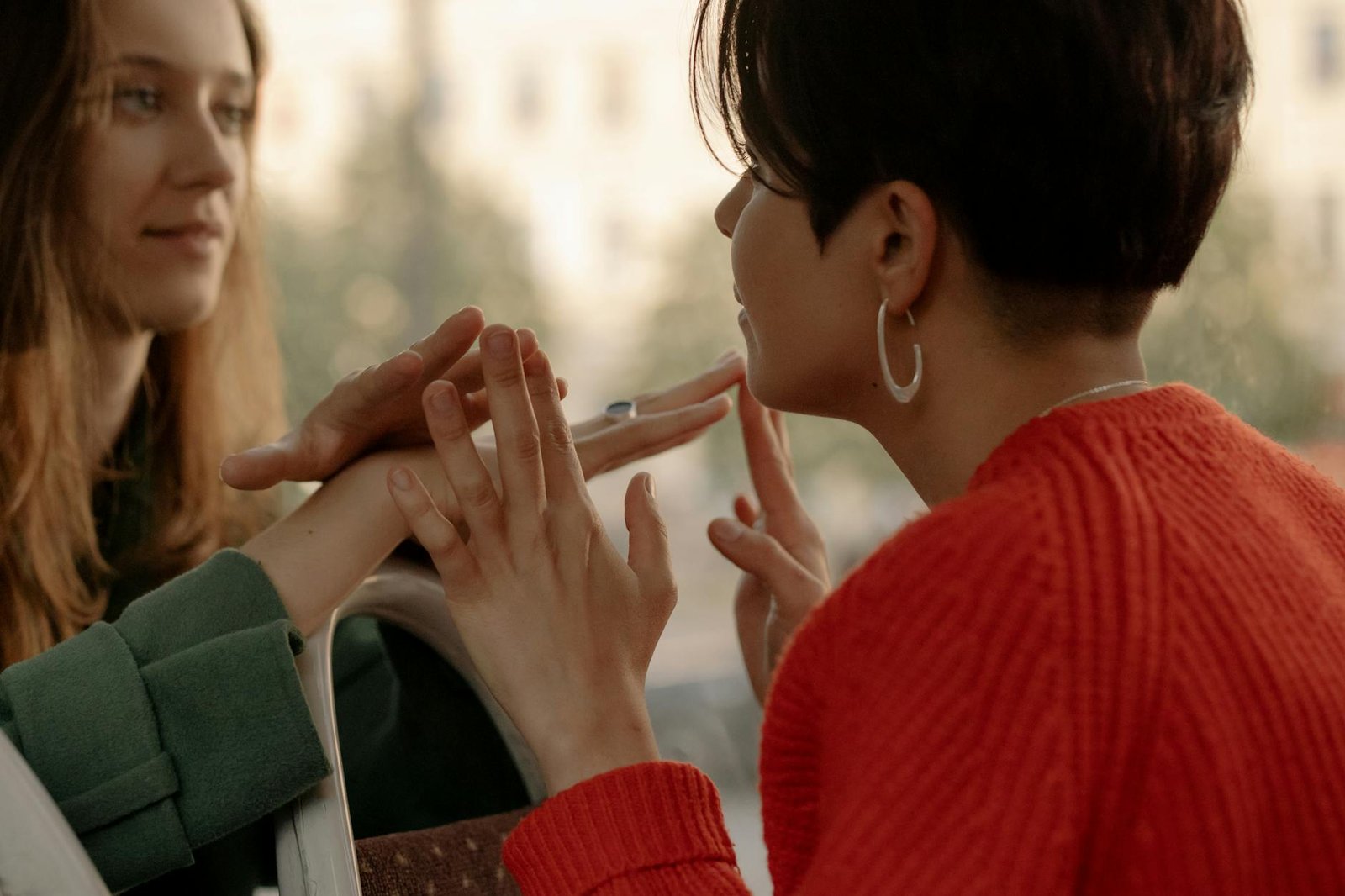 Two women share a tender moment, holding hands and making eye contact, expressing love and connection.