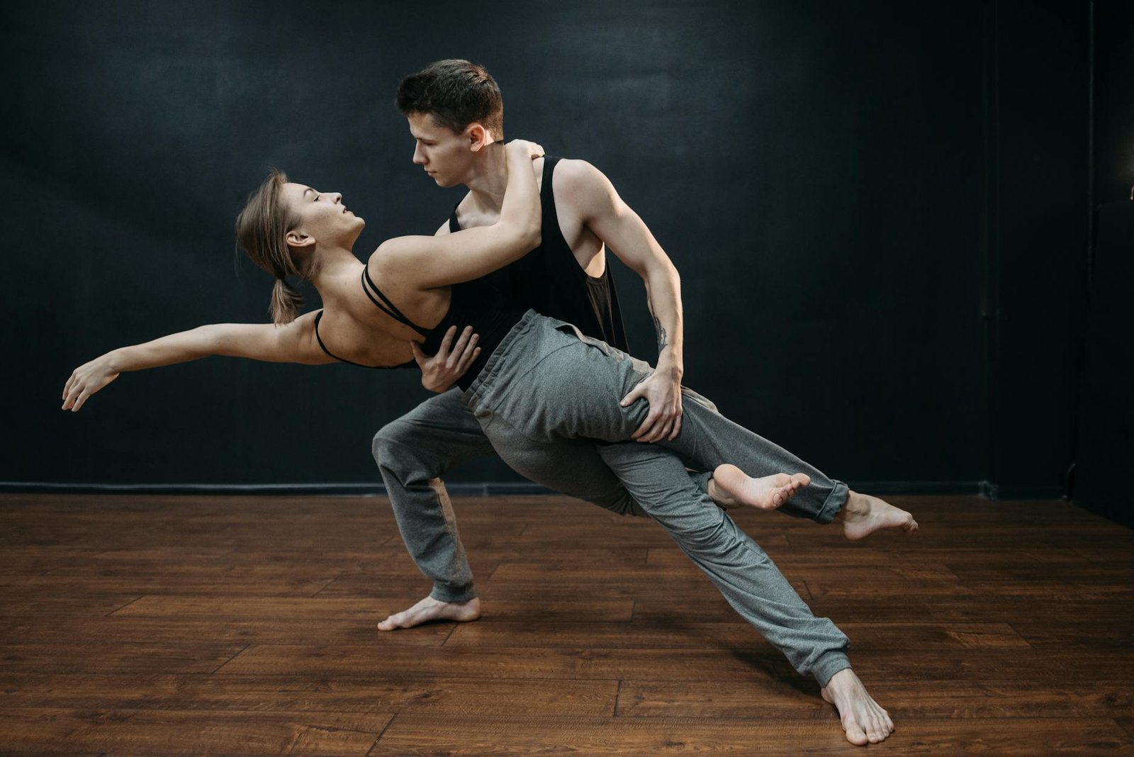 A couple performing an elegant contemporary dance routine in a studio, showcasing balance and flexibility.