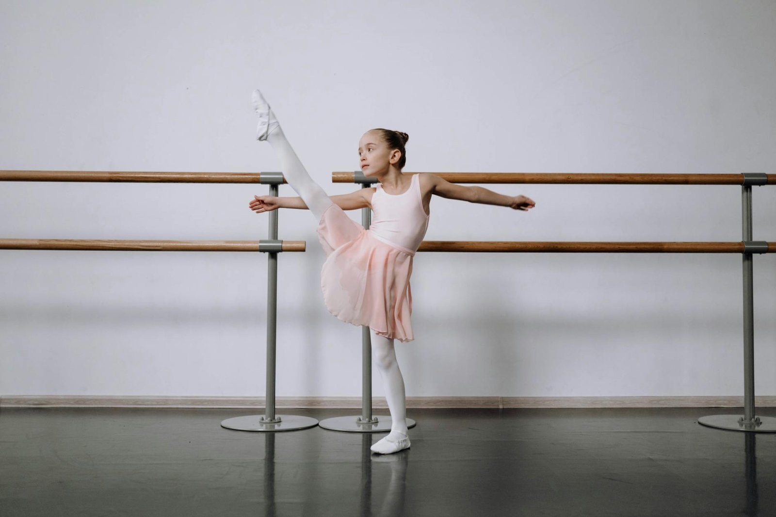 A young girl practicing ballet stretches at a studio, showcasing flexibility and grace.