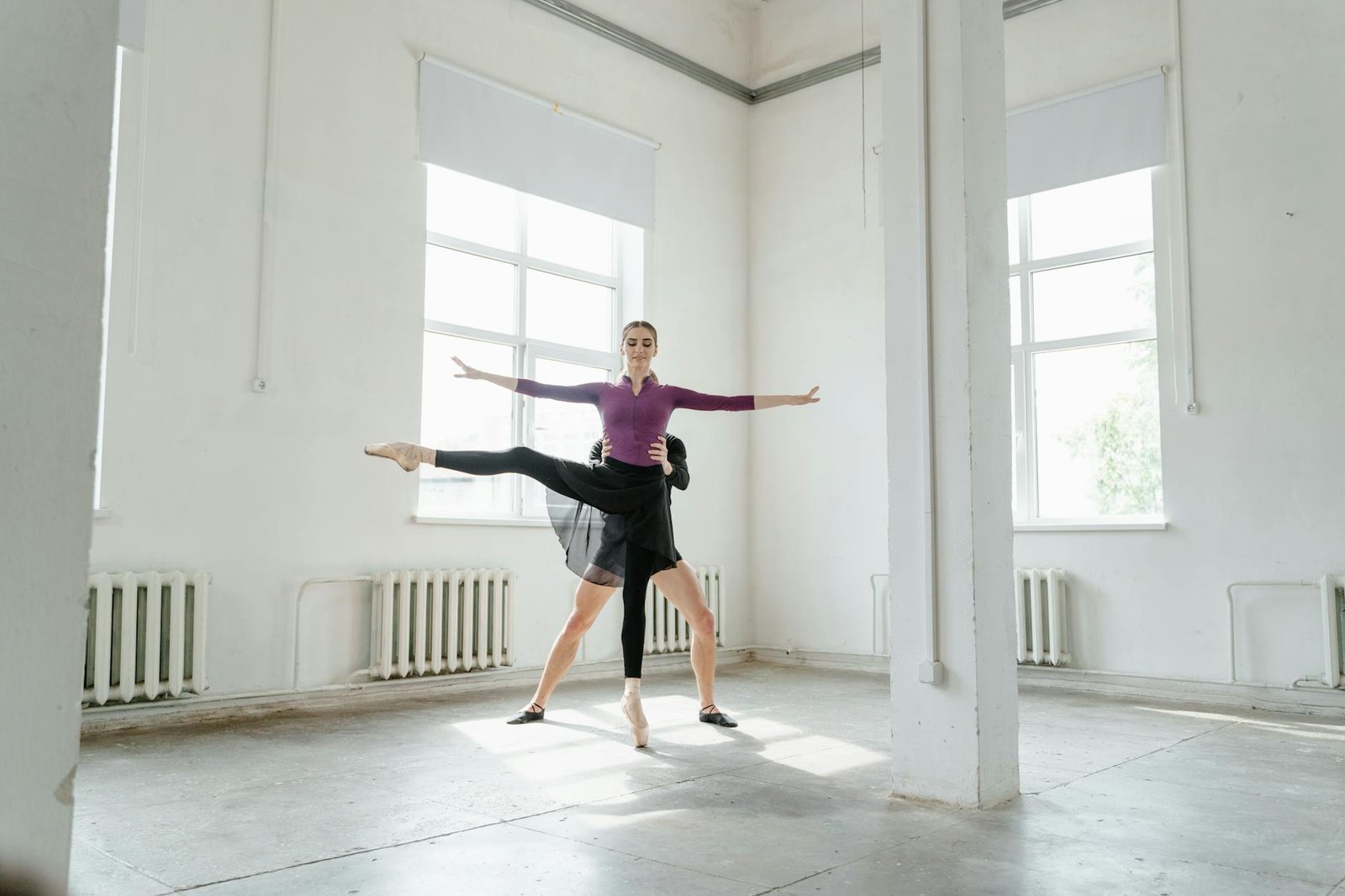 Ballet dancer gracefully poses in an airy dance studio, embodying elegance and precision.