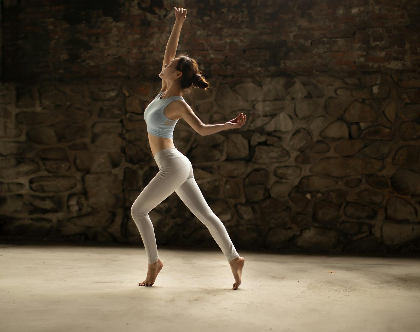 Graceful ballerina dancing barefoot in a rustic studio setting, exuding elegance and poise.