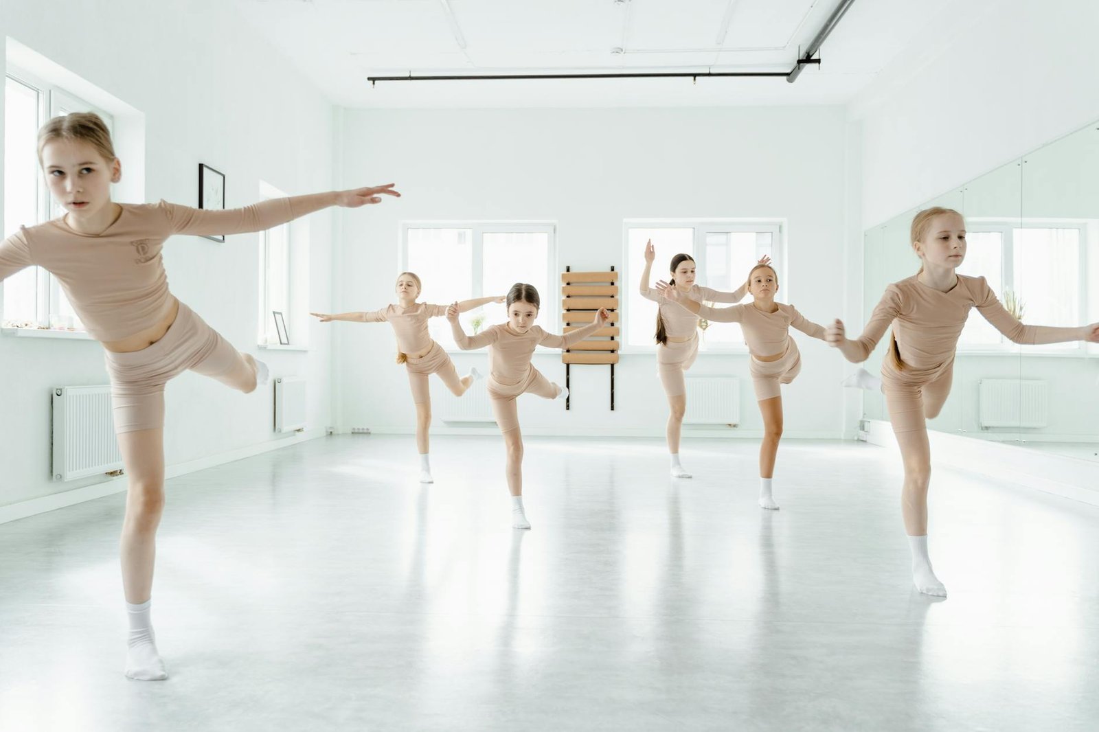 Group of young girls practicing ballet in a bright dance studio, full of energy and grace.