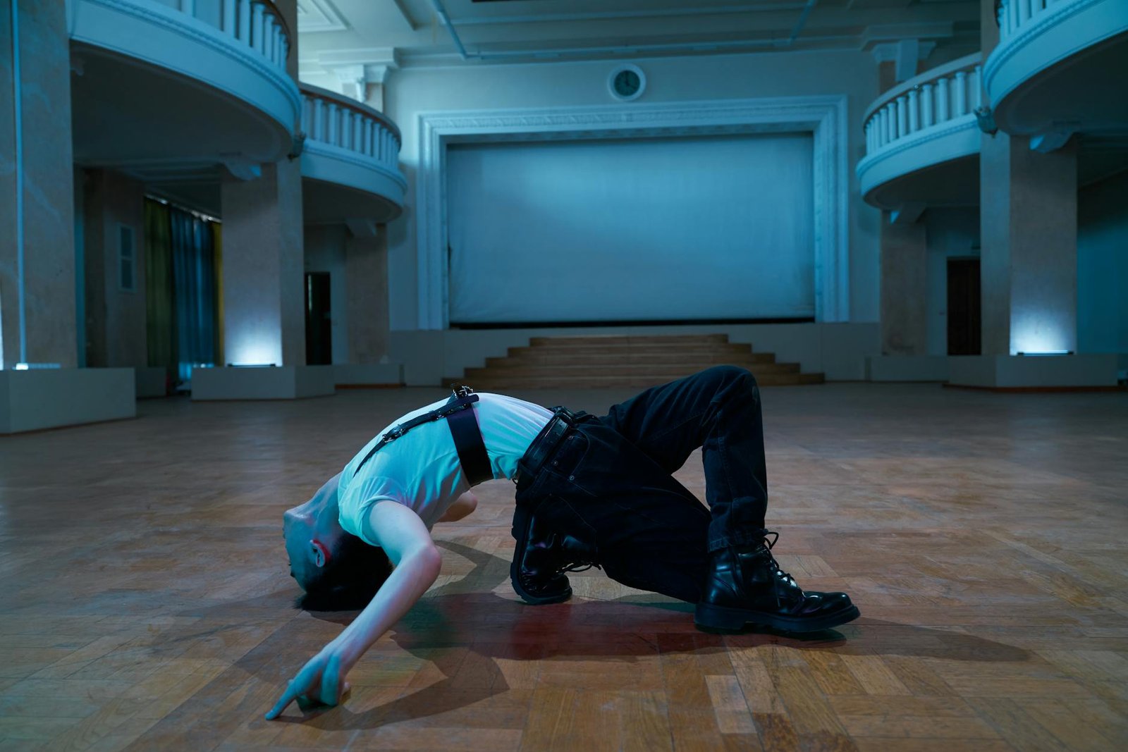 A male contemporary dancer striking a dynamic pose indoors, showcasing flexibility and artistry.