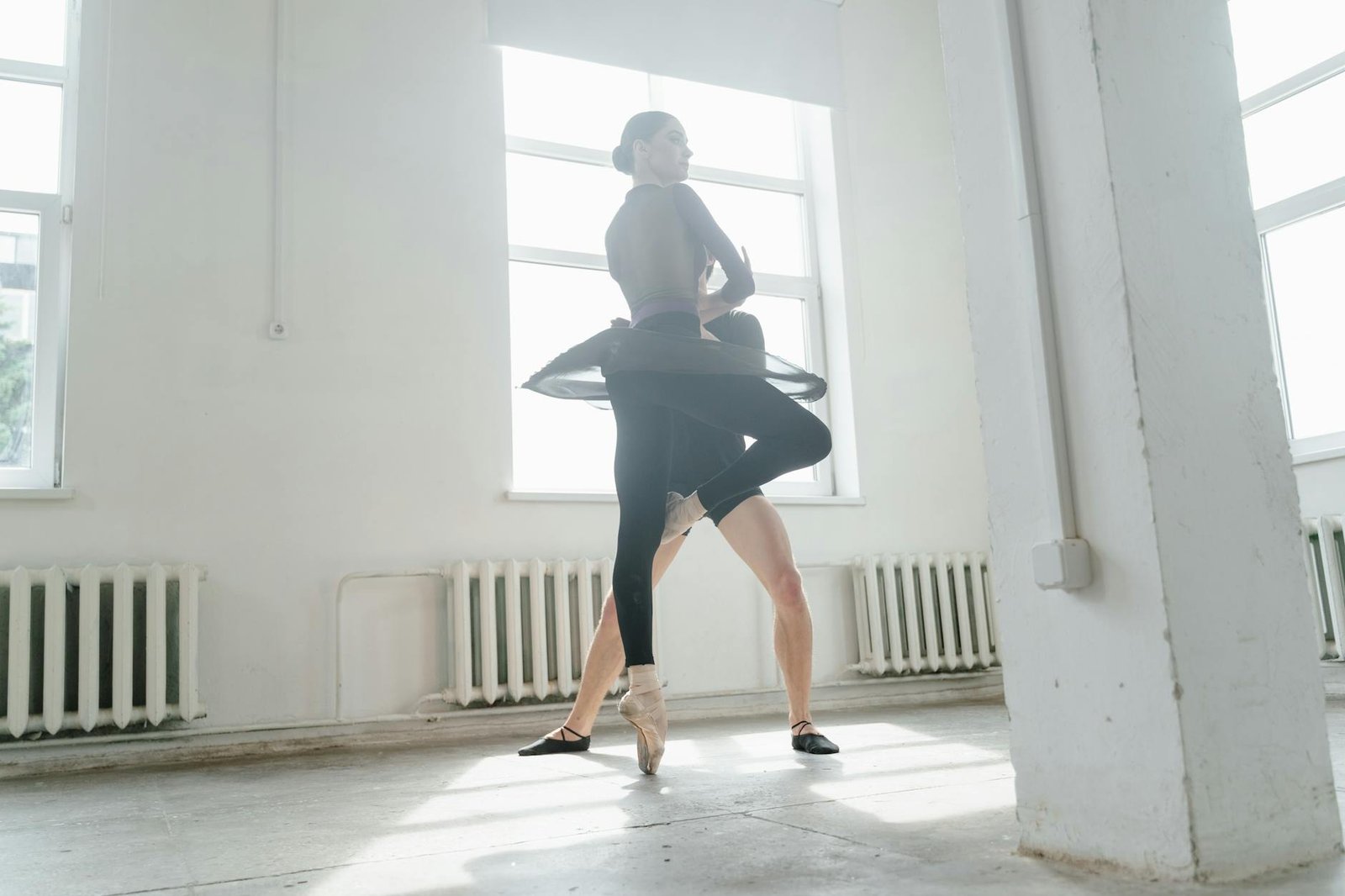 Graceful ballet dancers practicing pirouettes in a sunlit studio setting.
