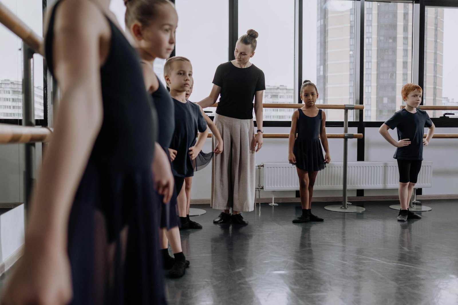 Children learning ballet in a dance studio with diverse peers and instructor guidance.