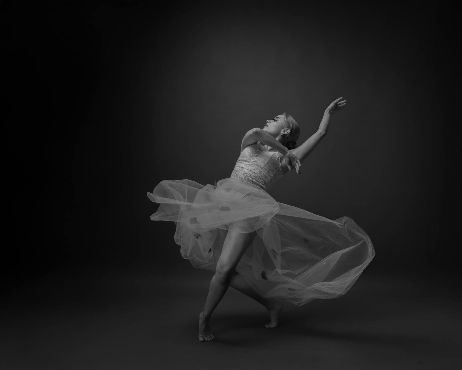 Graceful ballet dancer captured in fluid motion with a flowing dress in a studio setting.