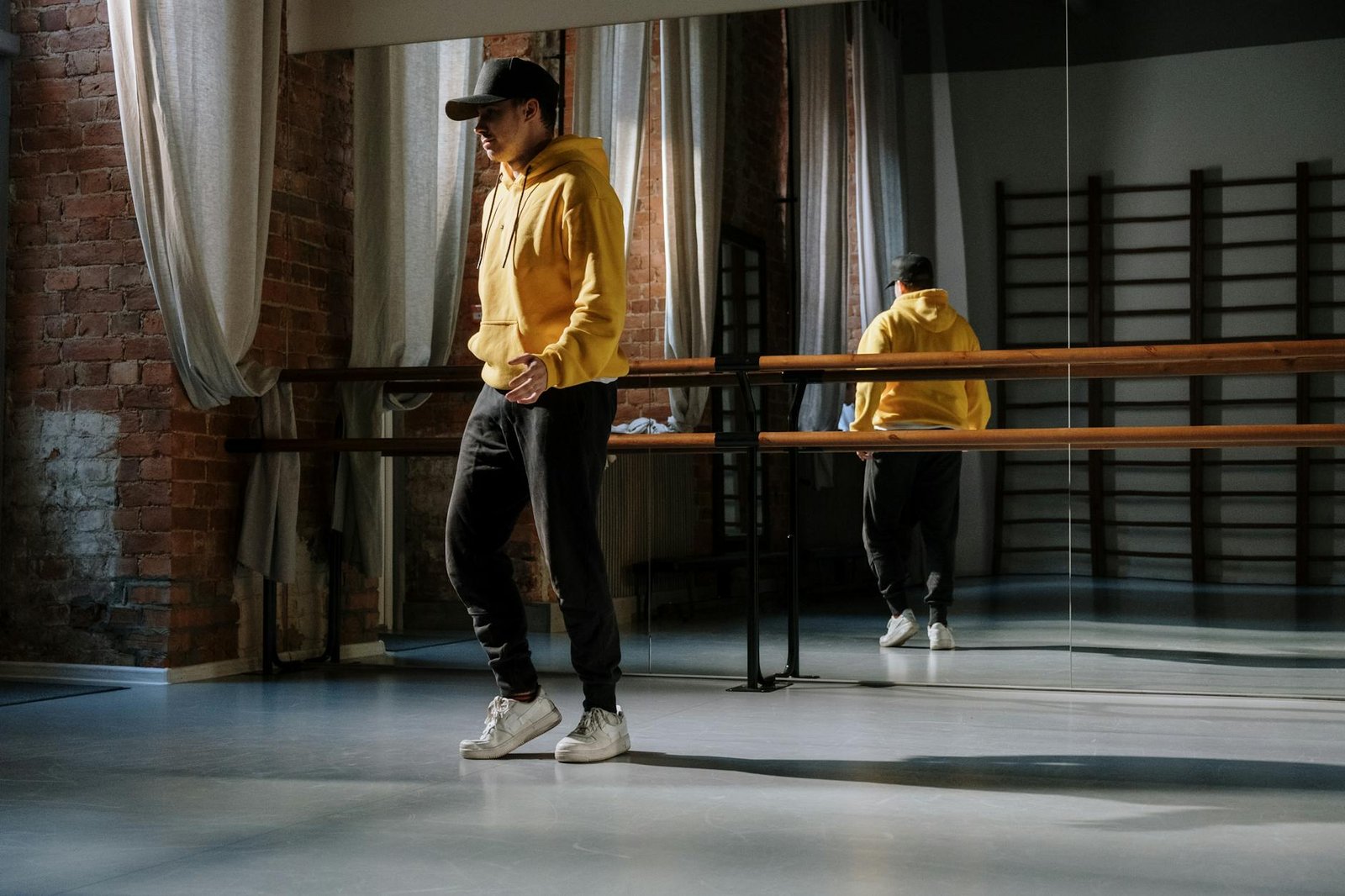 Male dancer practicing modern moves in a bright dance studio, wearing casual sportswear.