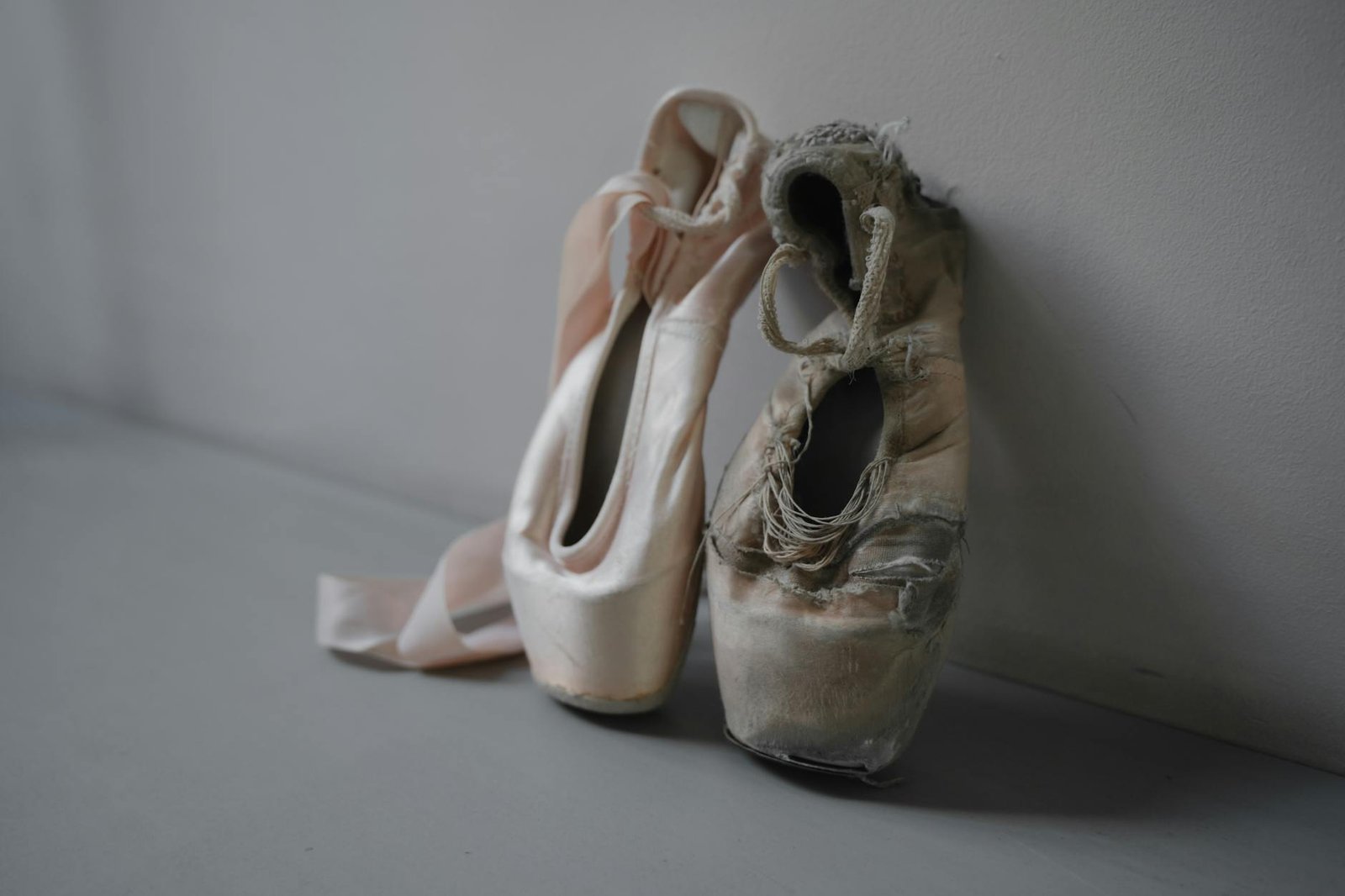 A close-up of a new and worn ballet pointe shoes symbolizing the journey of a dancer.