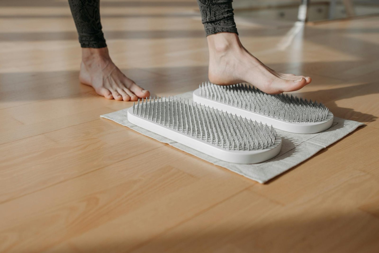Close-up of a person using acupressure mats on a wooden floor, promoting relaxation and health.