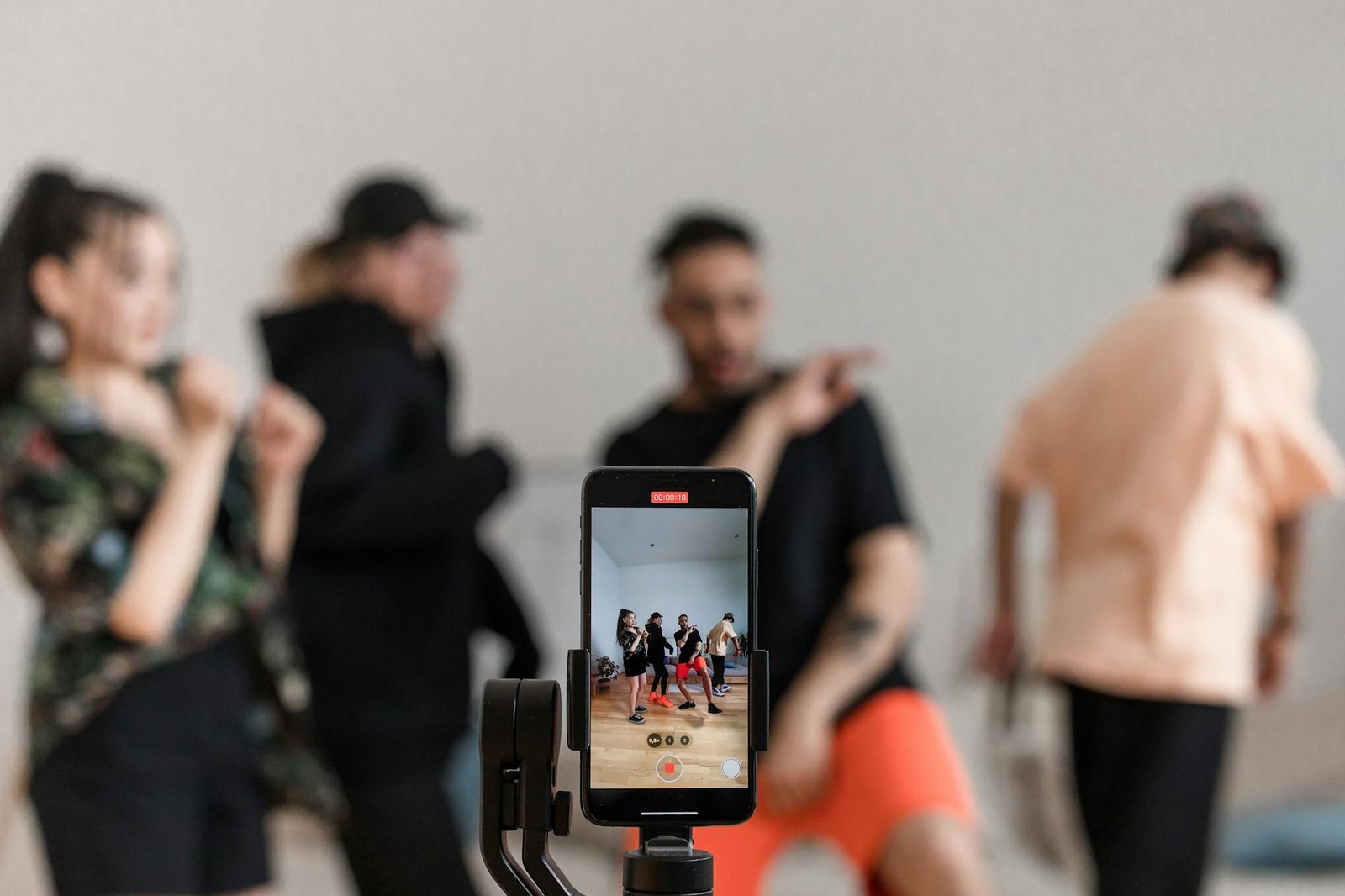 Group of dancers recording performance with smartphone on tripod, capturing trendy dance moves.