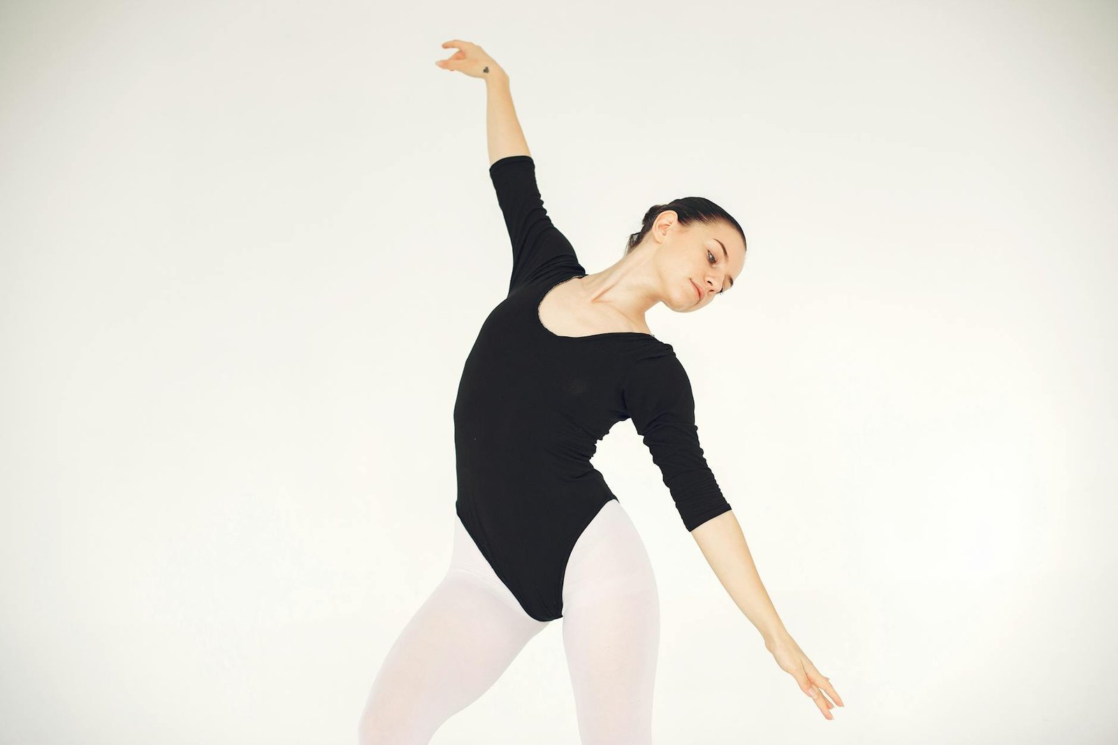 A graceful ballerina wearing a black leotard, striking a pose indoors.