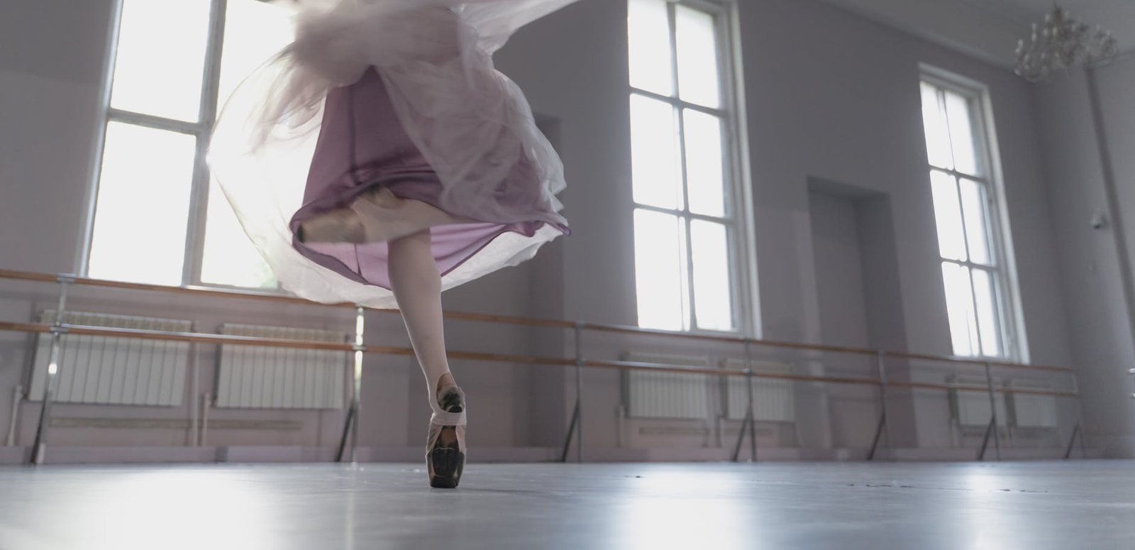 A close-up shot of a ballerina performing an elegant turn in a bright ballet studio.