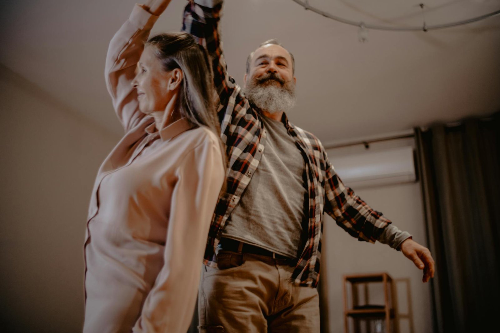 An elderly couple enjoying a dance together in their cozy living room, showcasing love and companionship.