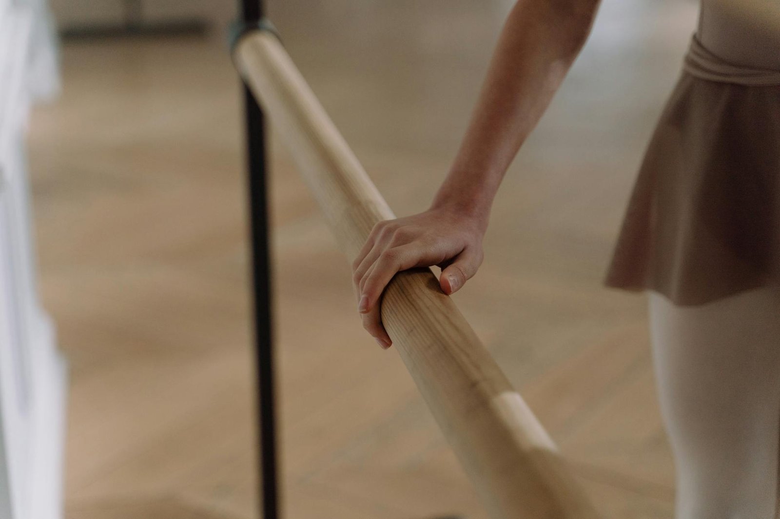 Elegant capture of a ballet dancer's hand on a barre, showcasing grace and focus.