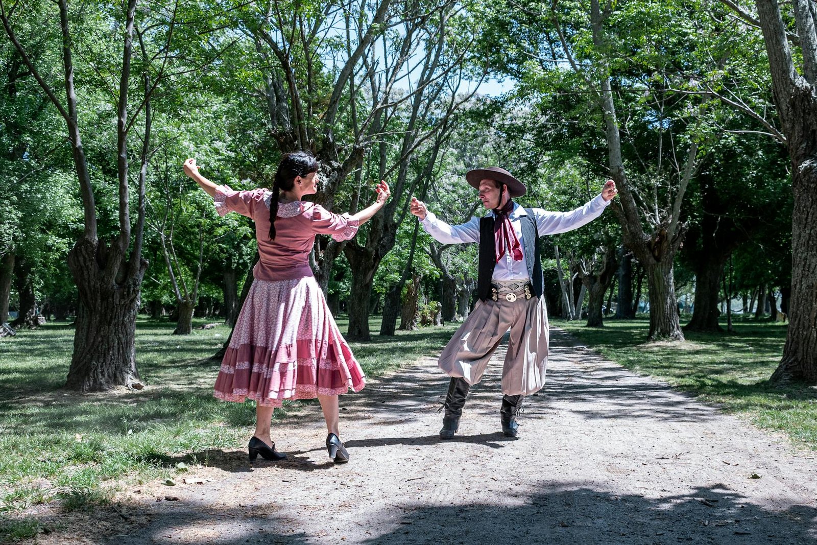 A couple performs a traditional gaucho dance in a sunny park in Chascomús, Argentina.