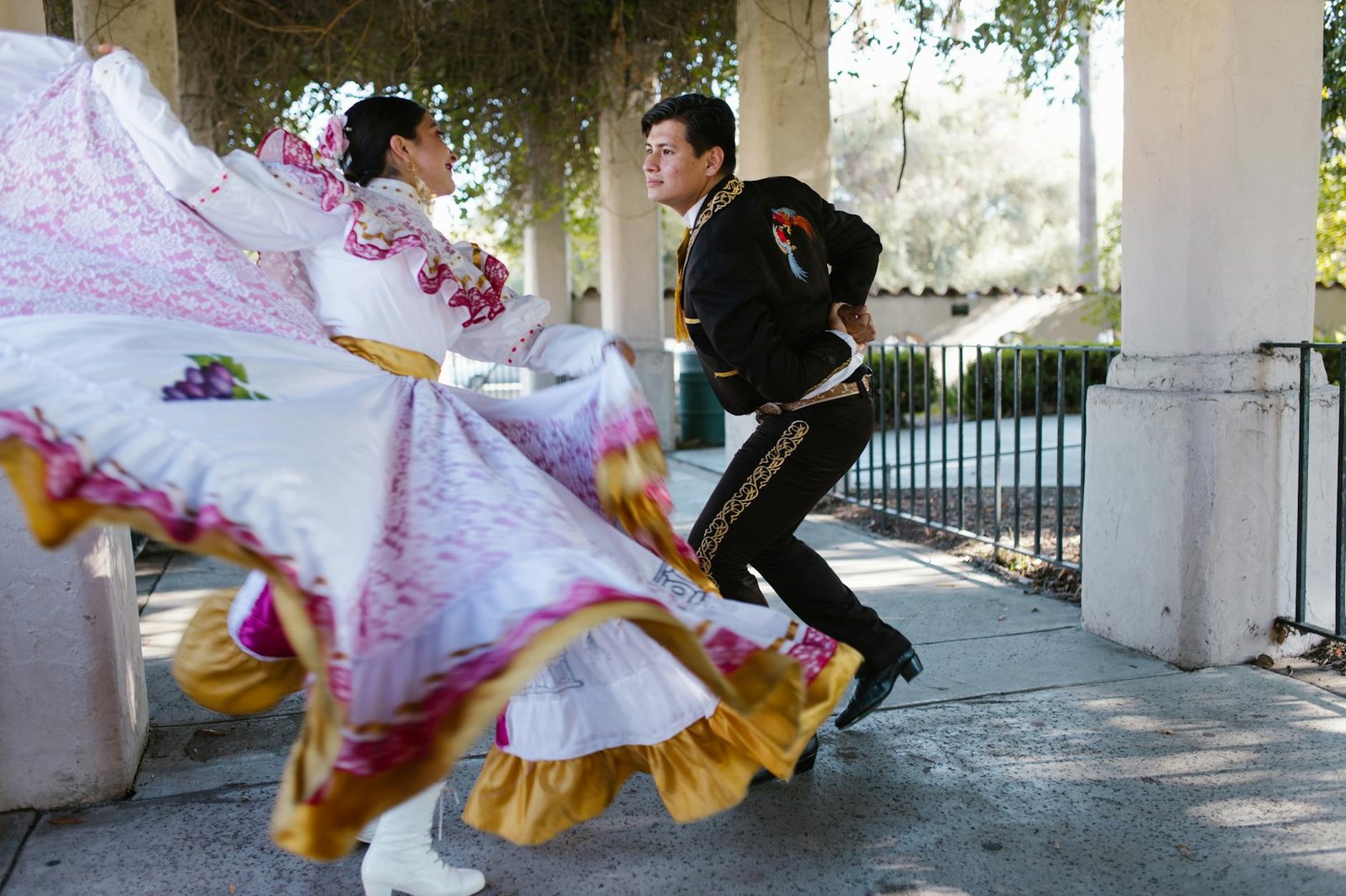 Couple performs traditional Mexican folk dance in colorful attire outdoors.