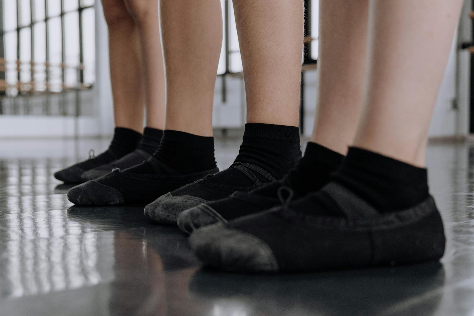 Close-up view of dancers' feet in ballet shoes standing on a studio floor, perfect for dance-related projects.