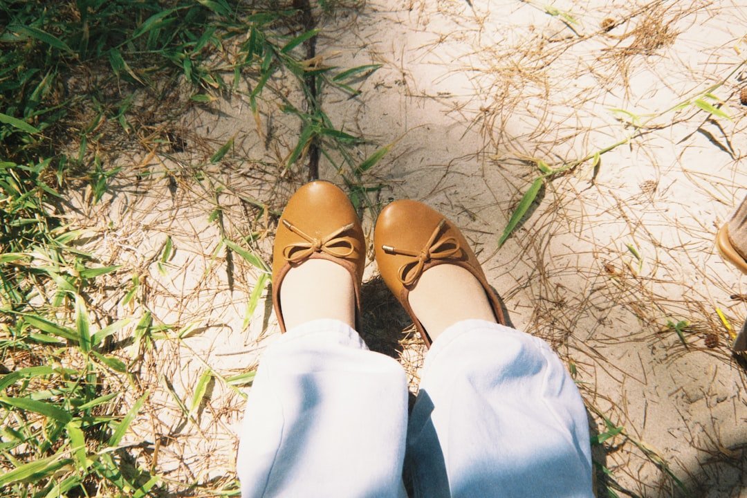 A person wearing brown shoes standing in the grass