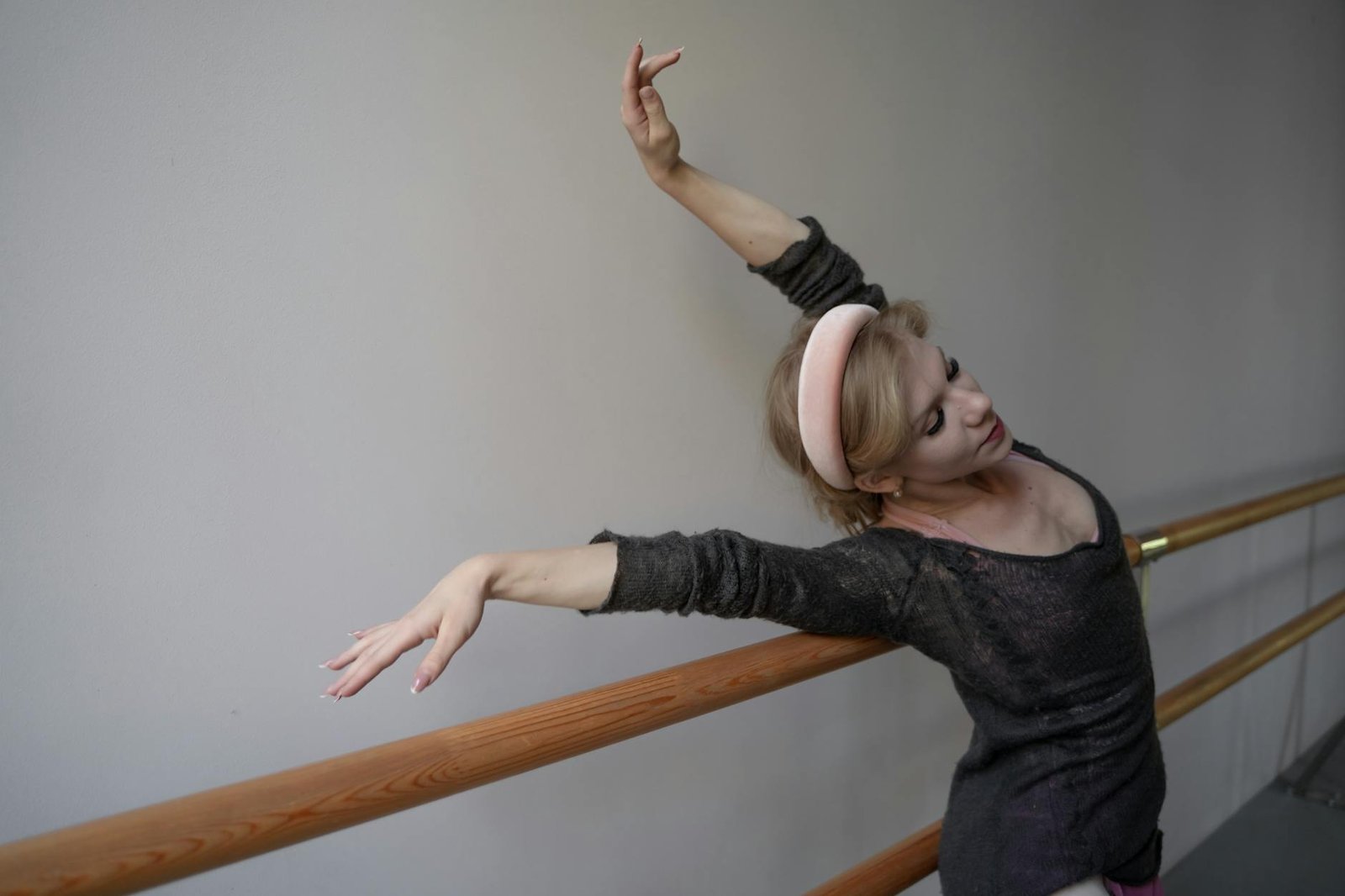 Ballerina gracefully practicing ballet at a barre indoors, focusing on form.