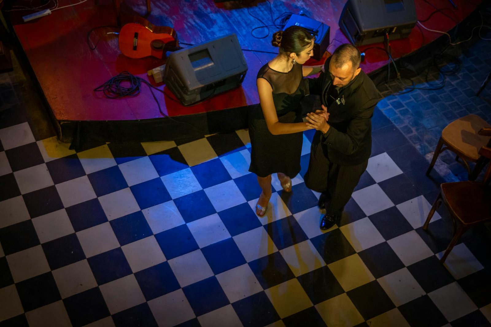 A couple gracefully dances tango in Mar del Plata, Argentina, on a checkered floor.