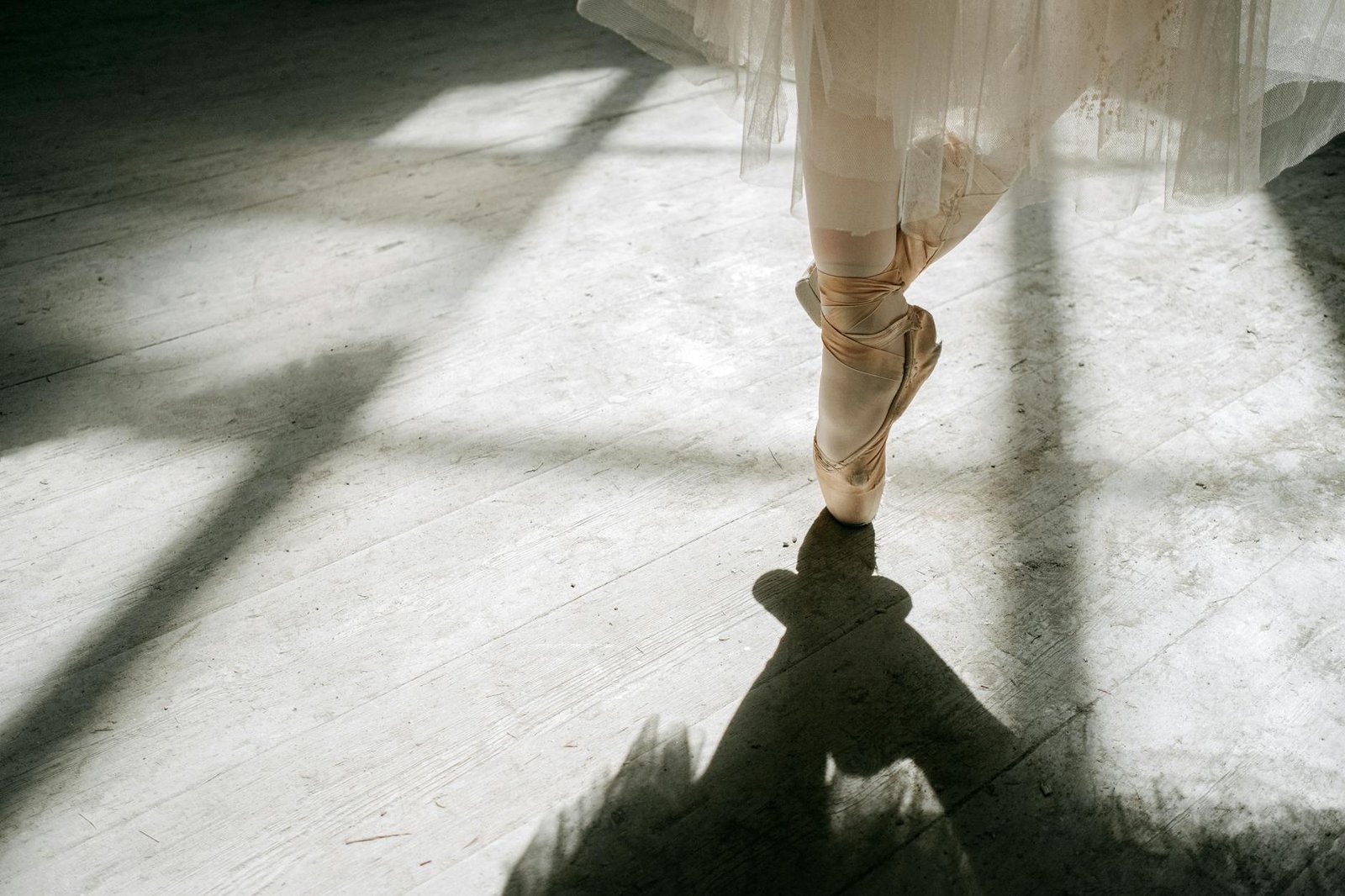 A graceful ballerina on pointe showing strength and balance, casting a shadow.
