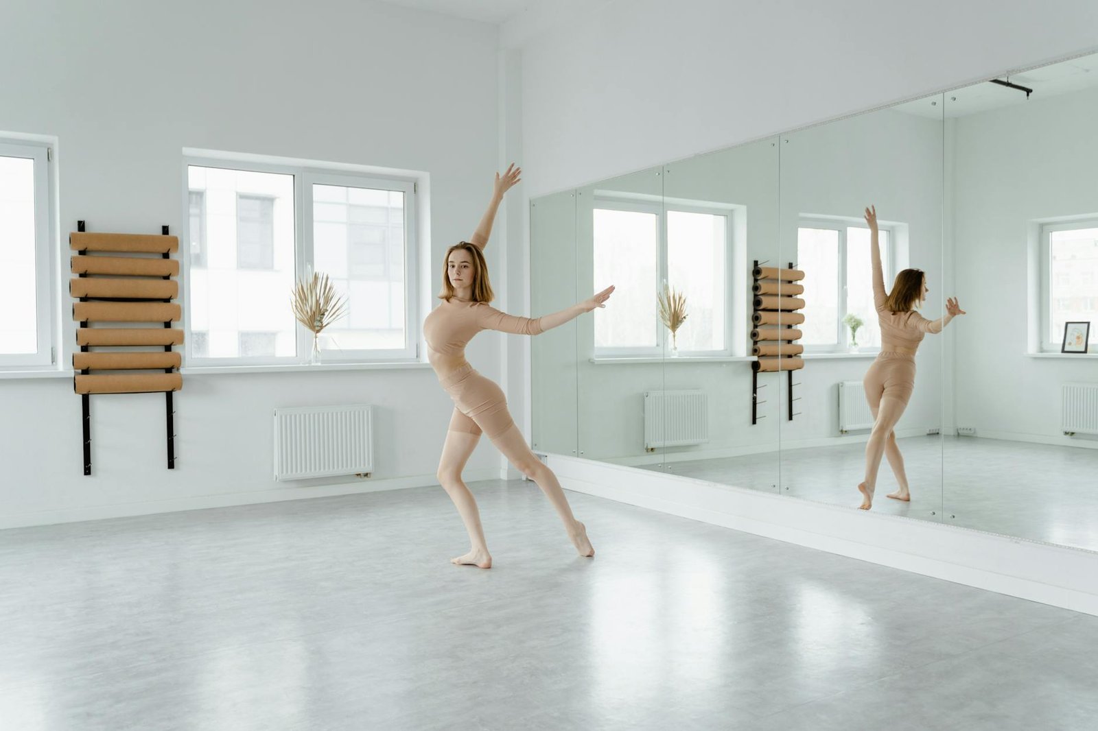 A graceful ballet dancer poses in a mirrored studio, showcasing elegance and grace.