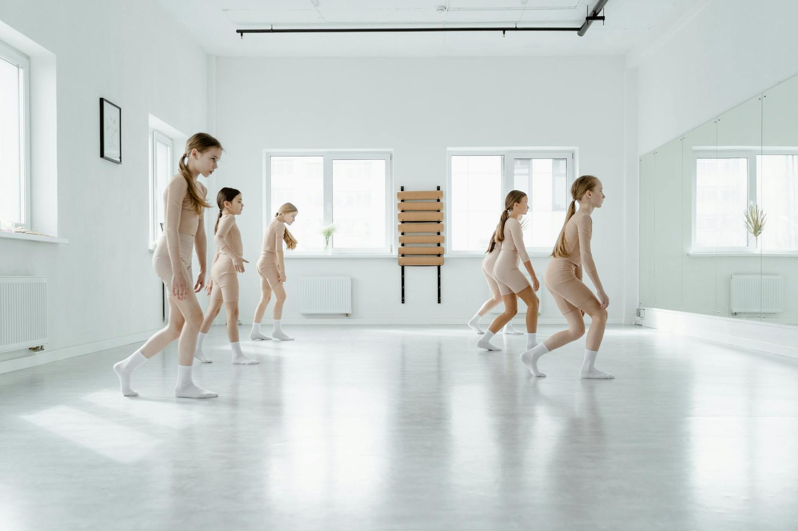 A group of young girls practicing dance in a bright, airy studio.