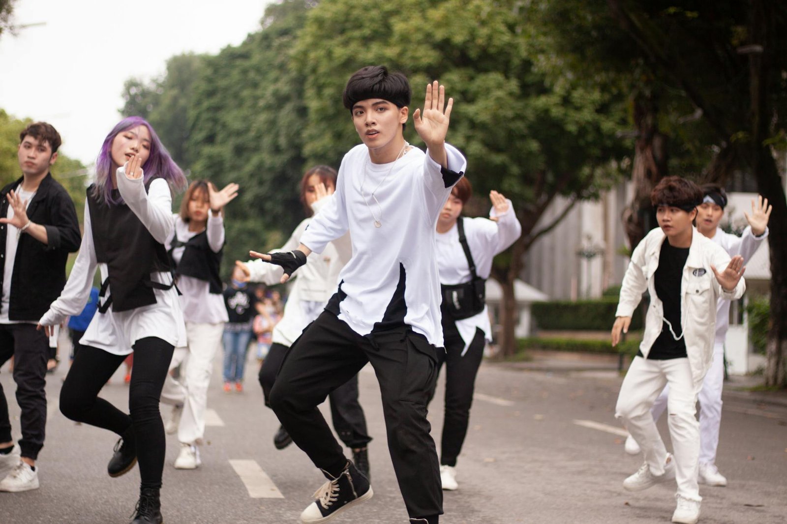 Group of young adults performing an energetic street dance routine outdoors.