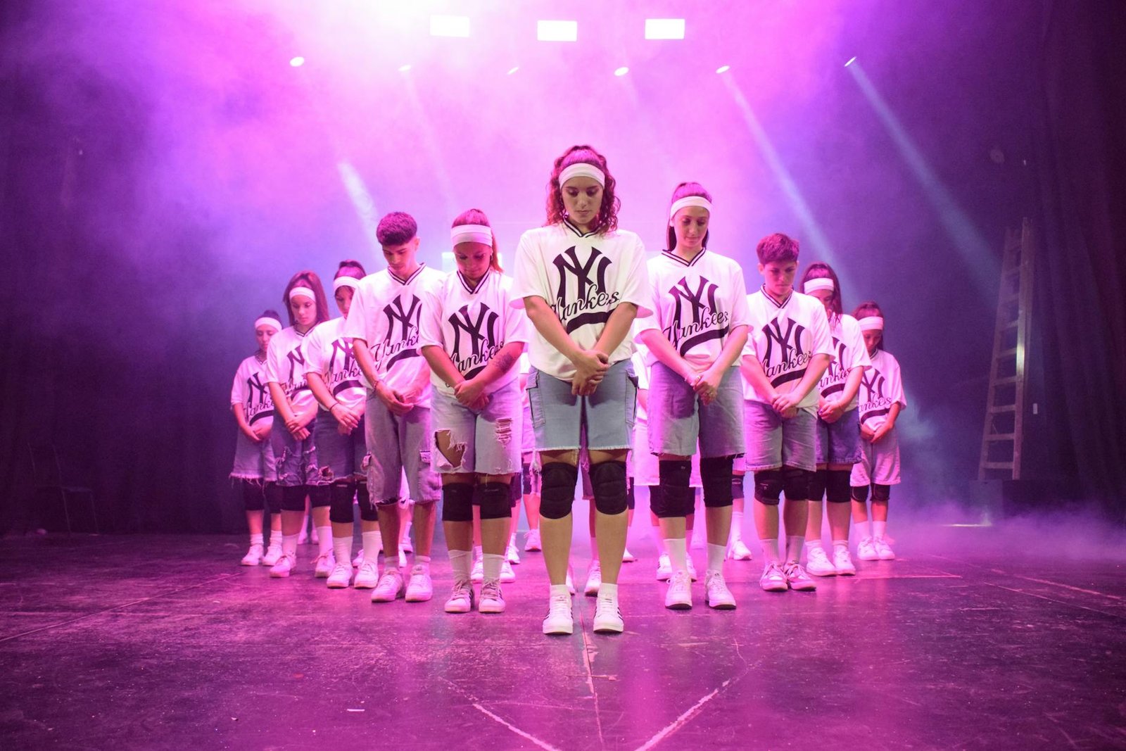 Young dance crew performing in matching uniforms under vibrant stage lights.