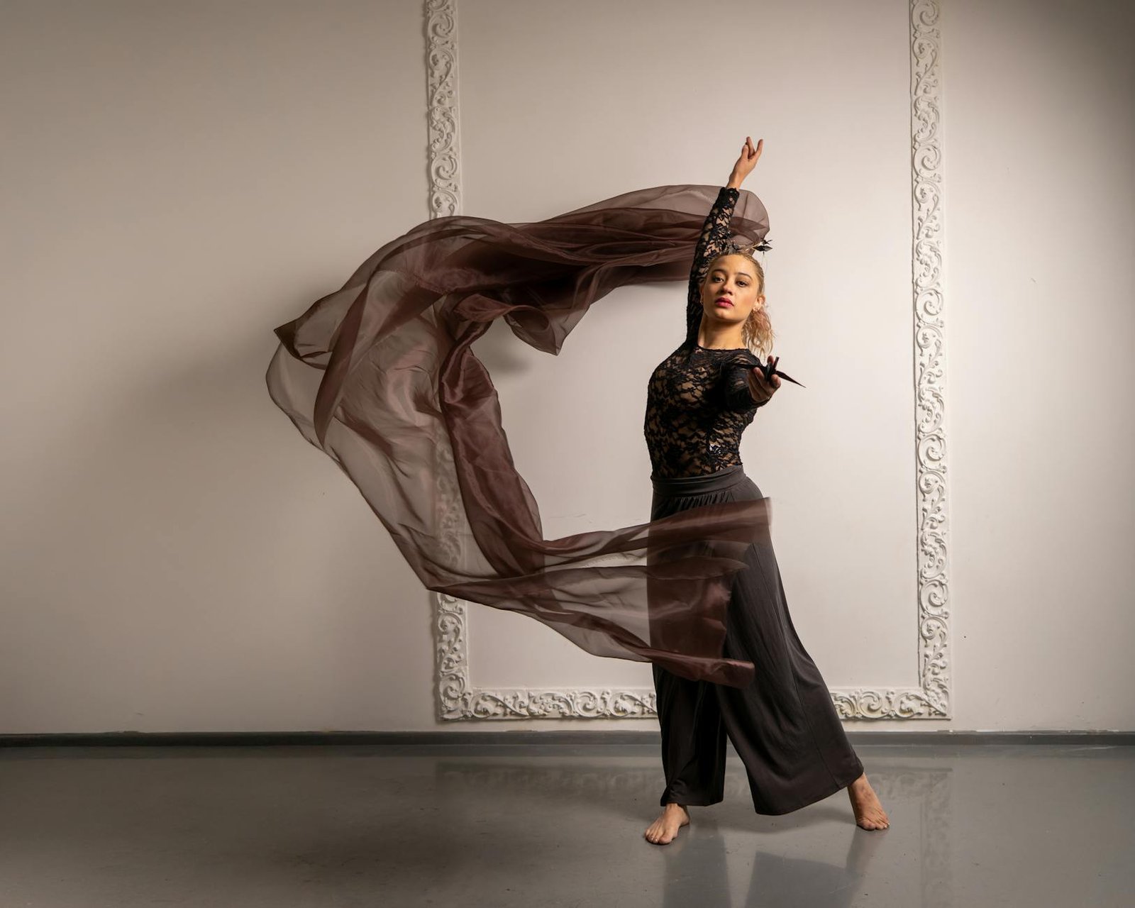 Female dancer in flowing motion with fabric in a minimalist studio setting.