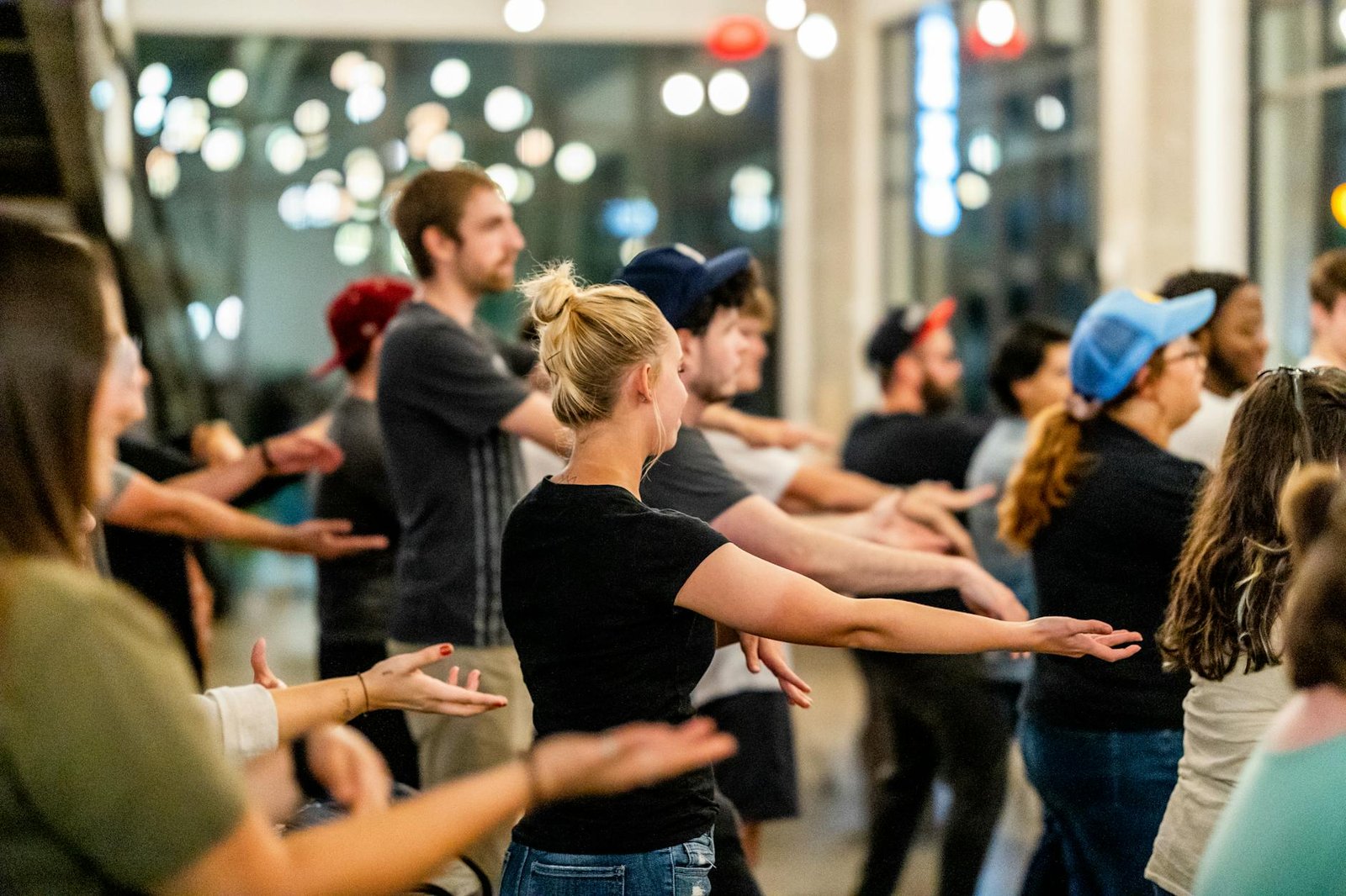 A diverse group of adults practicing dance in a bright indoor studio setting.