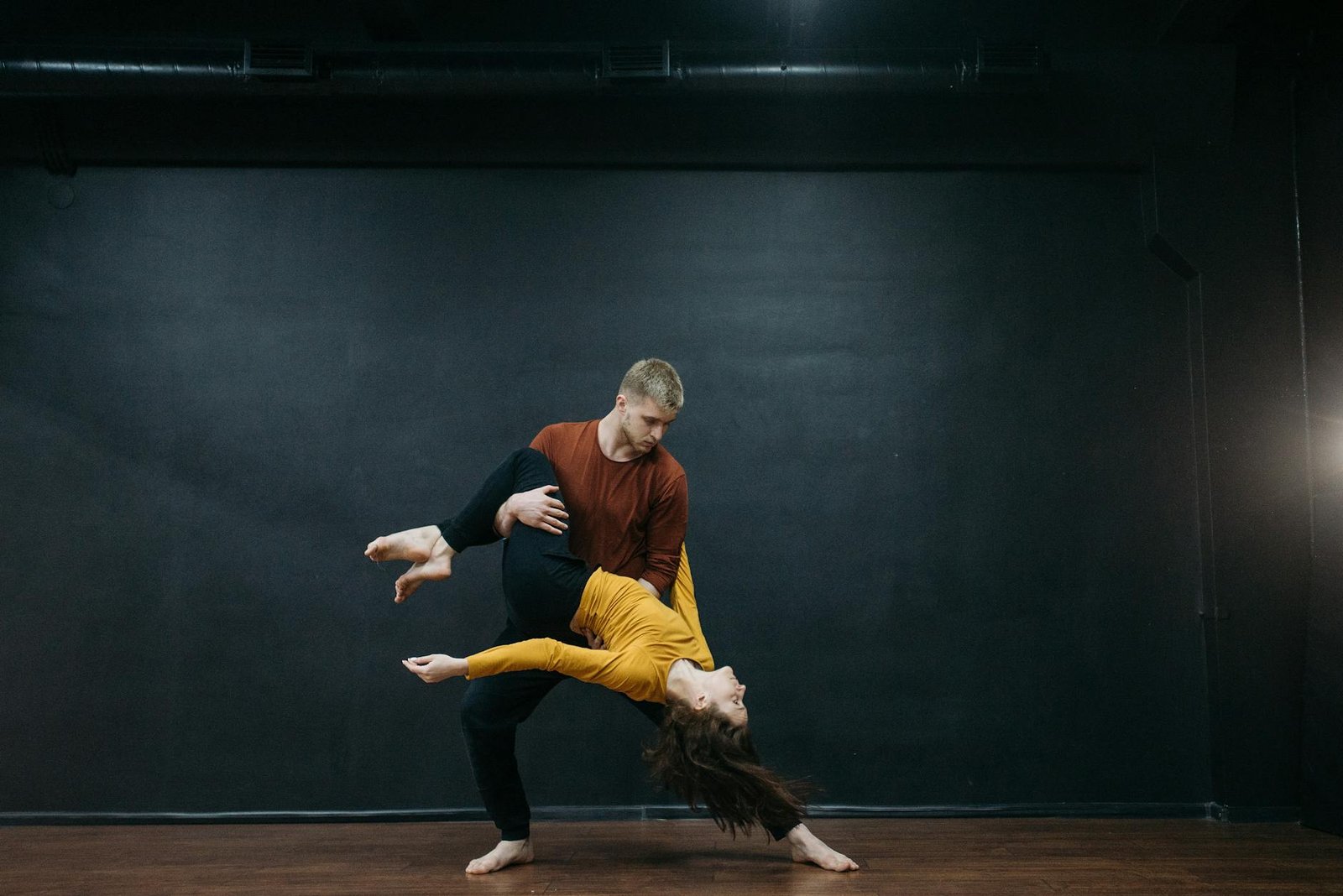 A couple performing an expressive dance move in a studio setting.