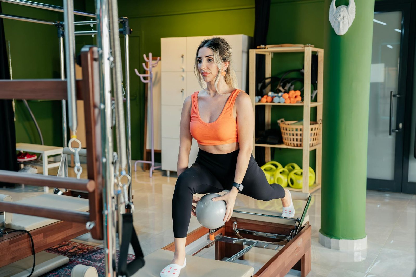 A woman practicing reformer pilates, focusing on balance and strength in a gym studio.