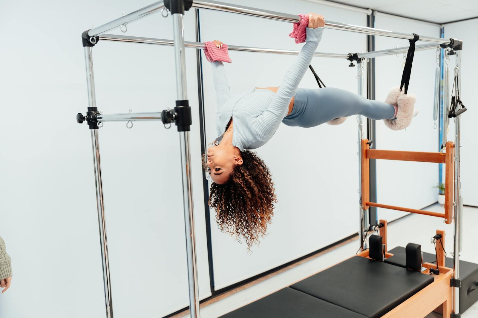 Fit woman doing pilates exercise on reformer equipment in a fitness studio.