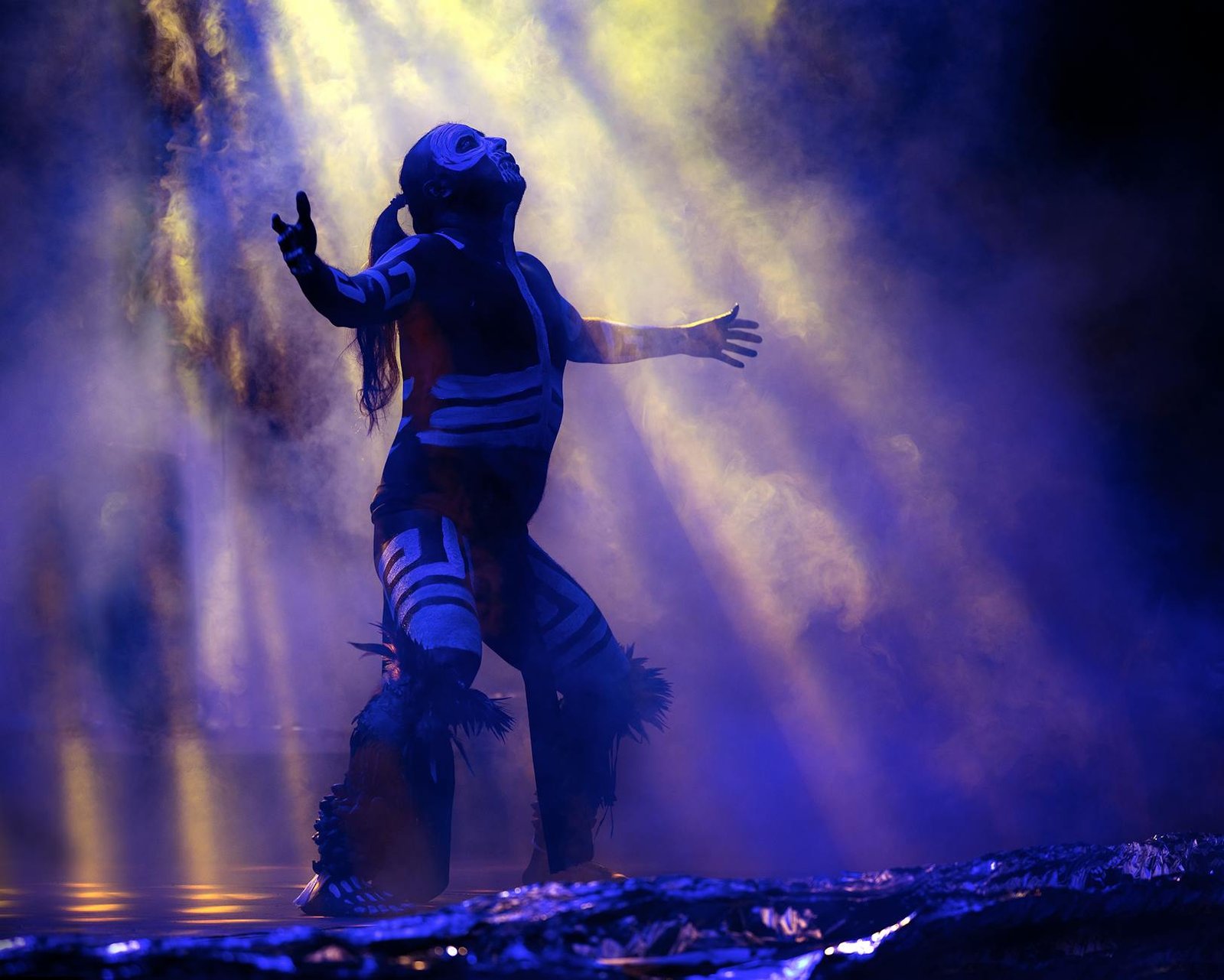 A dancer in indigenous attire performs a mystical ritual under dramatic lighting in Puebla, Mexico.