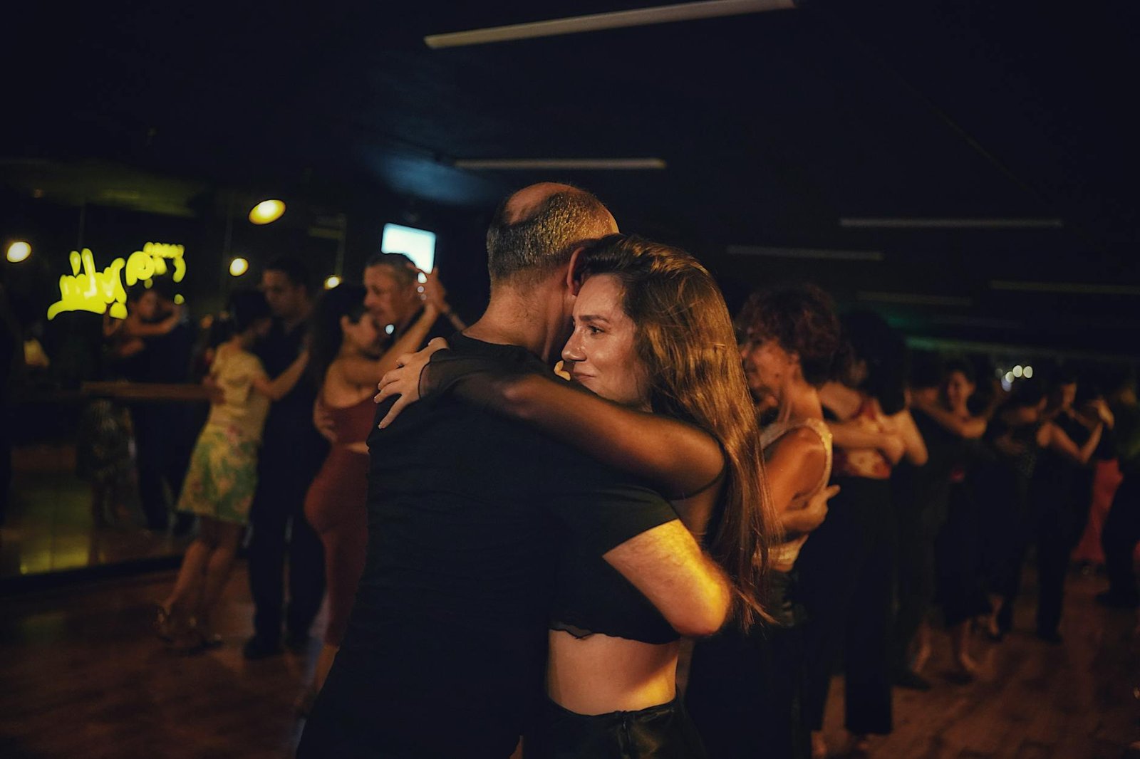 A captivating image of a couple dancing closely in a dimly lit nightclub setting.