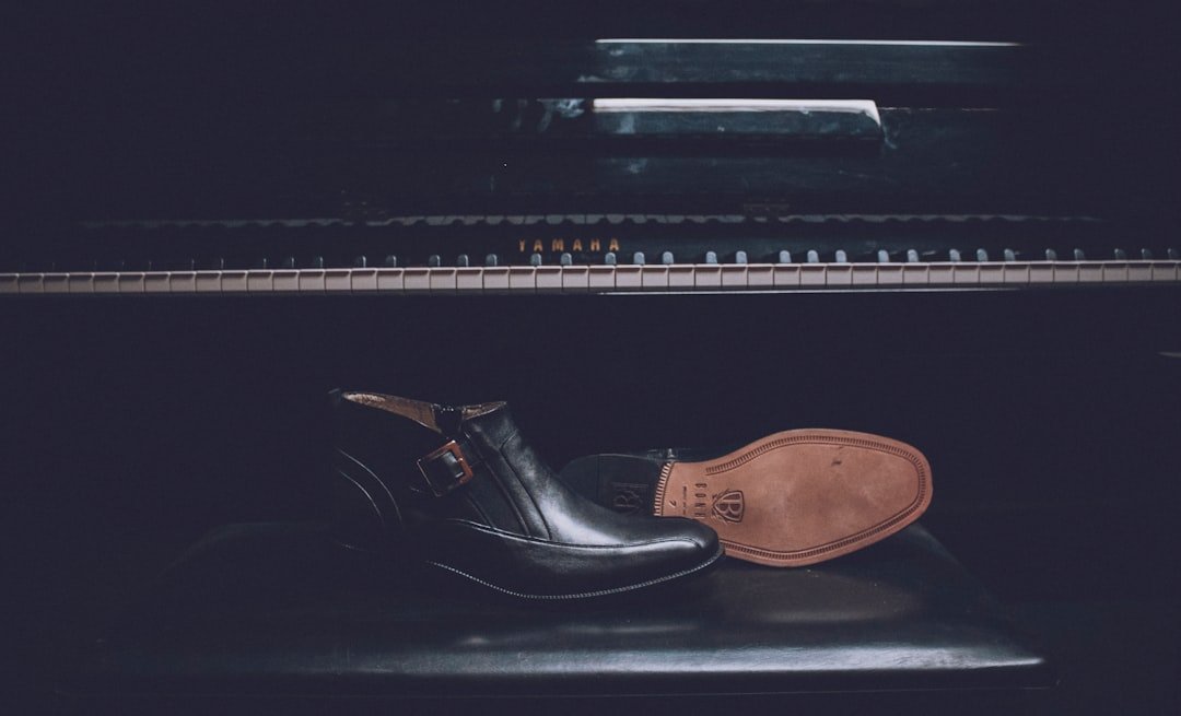 pair of black patent leather dress shoes on piano seat
