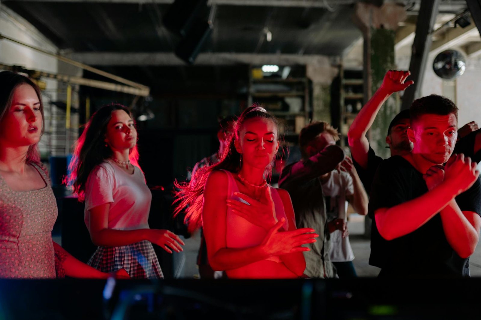 A lively nightclub scene with diverse groups enjoying music and dance under colorful lights.