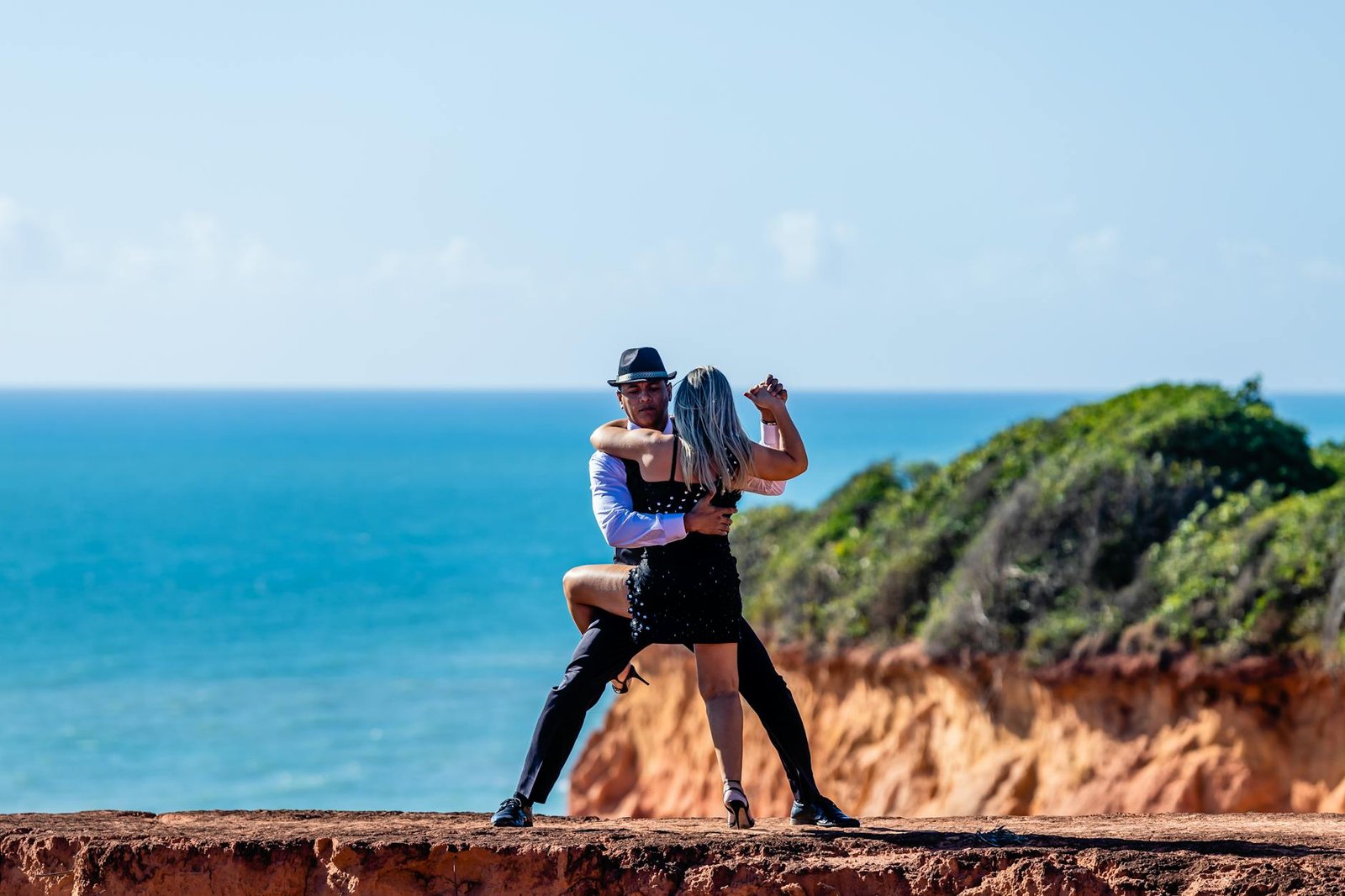 A couple elegantly dancing tango on the scenic cliffs of Brazil with the ocean as a backdrop.