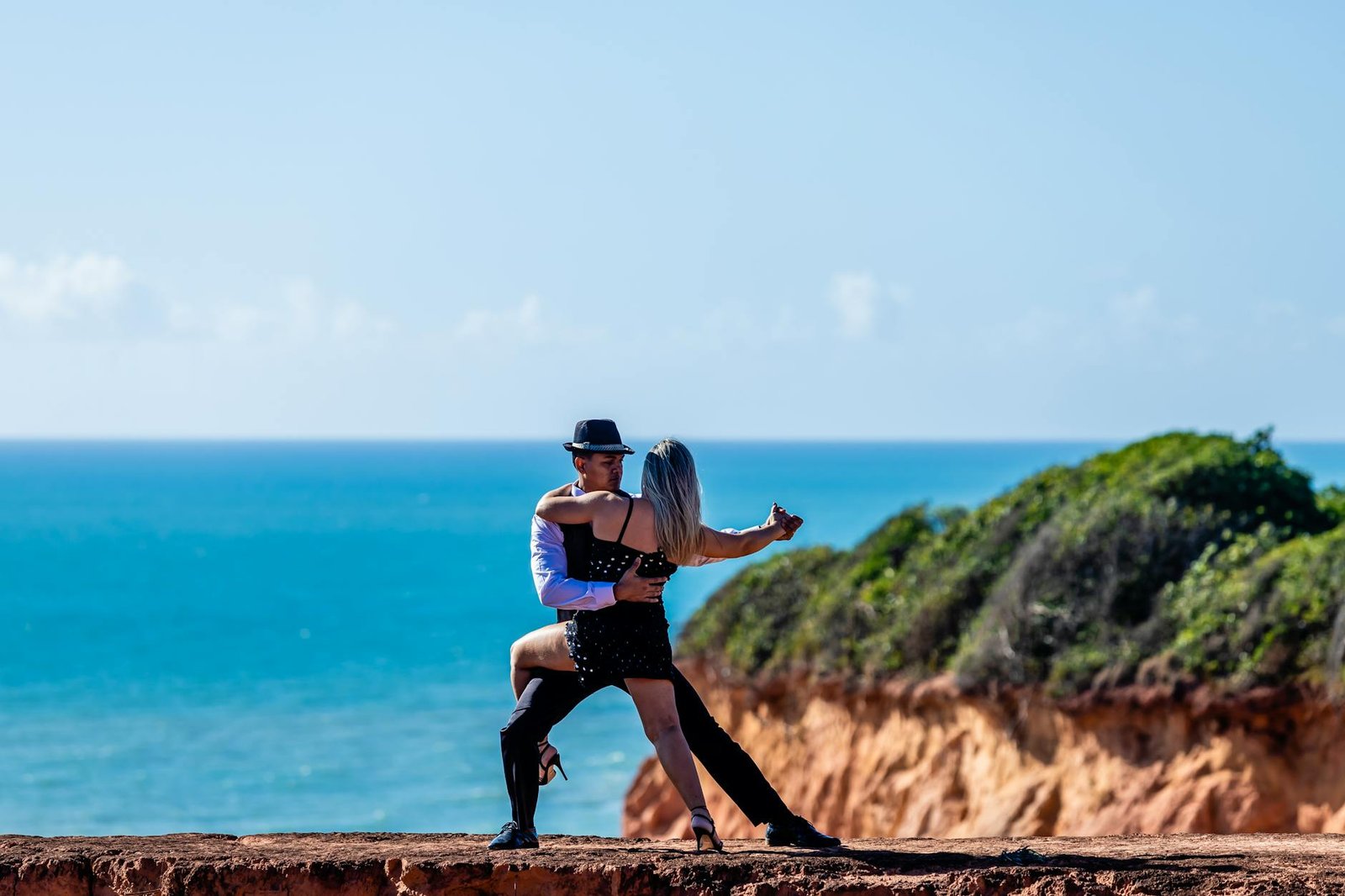 A couple elegantly dances on a cliffside with a stunning ocean backdrop in Paraíba, Brazil.